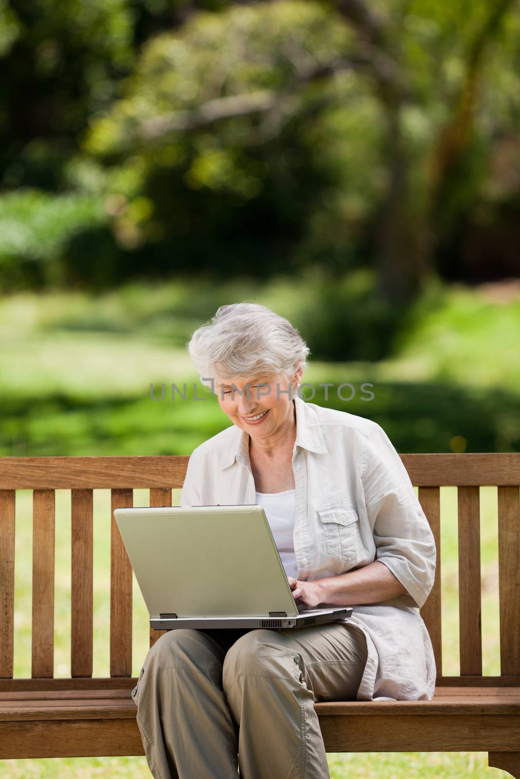 Mature woman working on her laptop on the bench by Wavebreakmedia