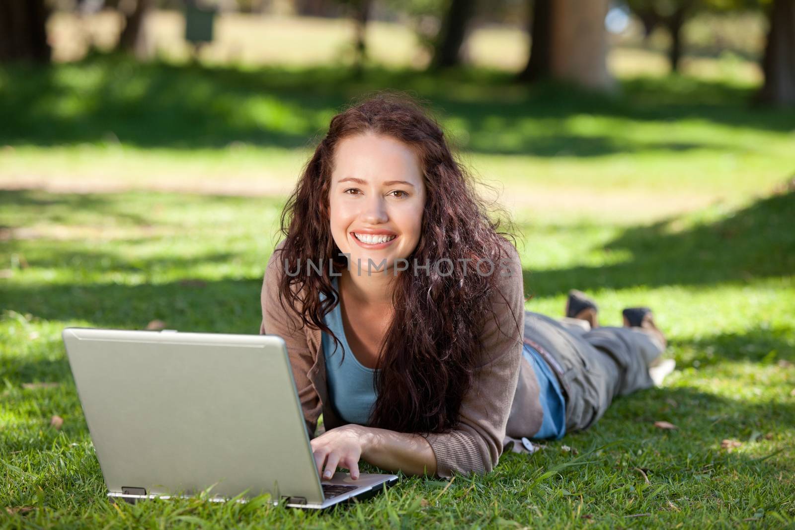 Woman working on her laptop in the park by Wavebreakmedia