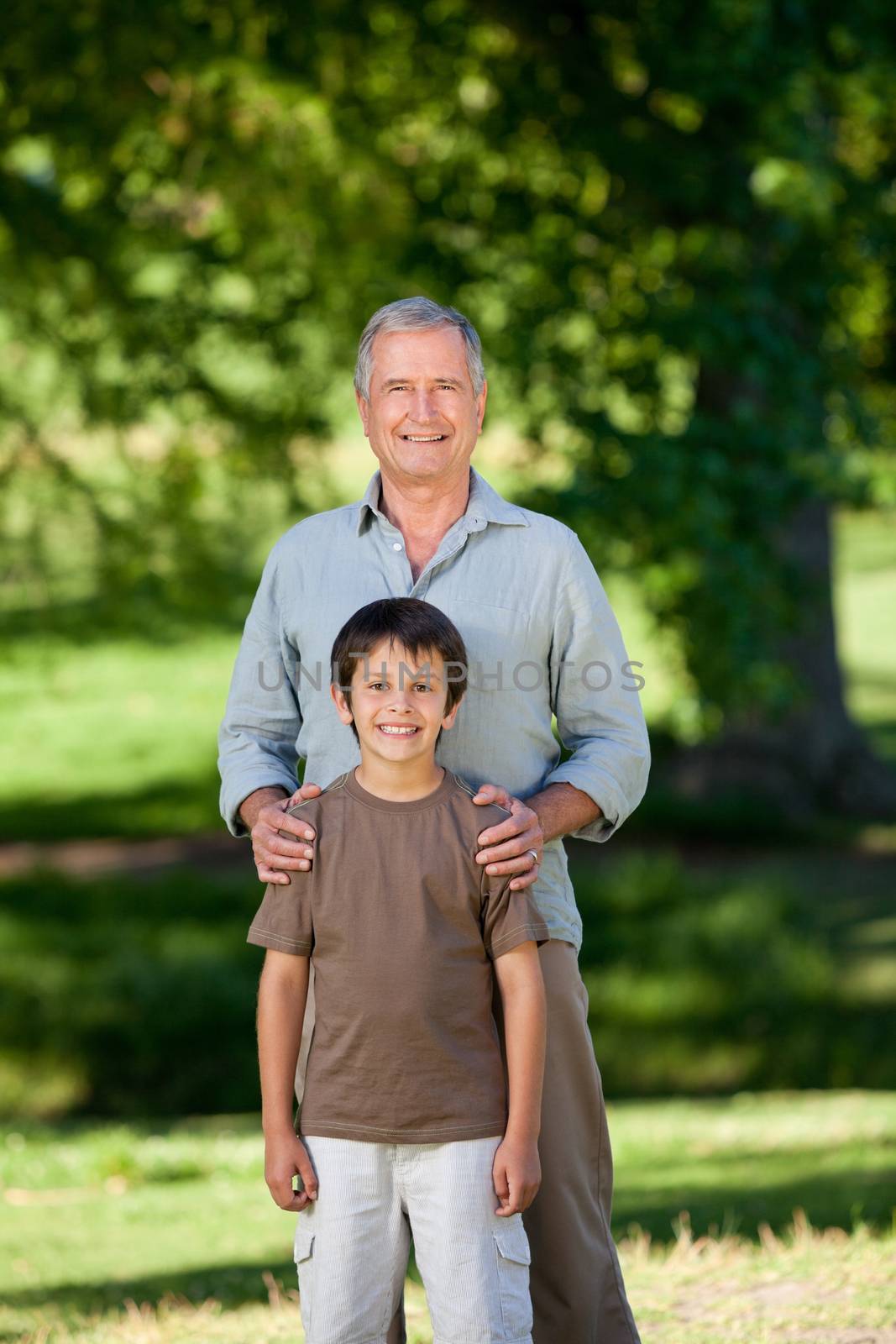 Grandather and his grandson looking at the camera in the park by Wavebreakmedia