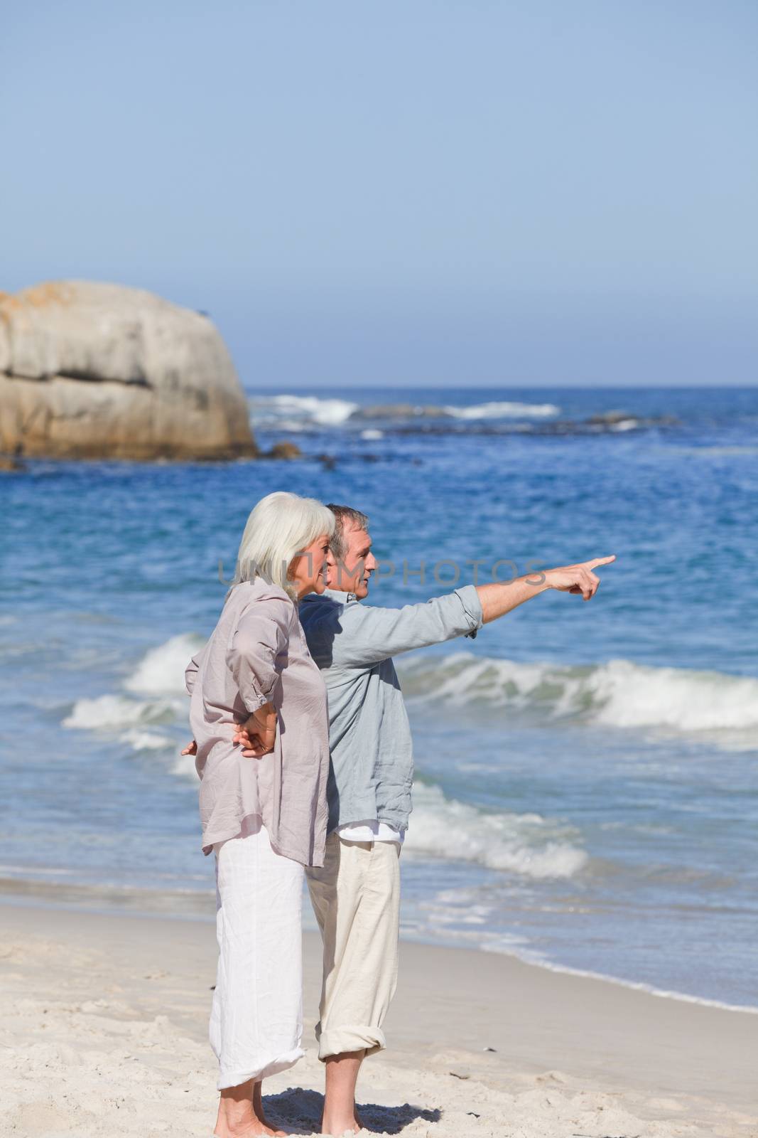 Elderly couple walking on the beach by Wavebreakmedia