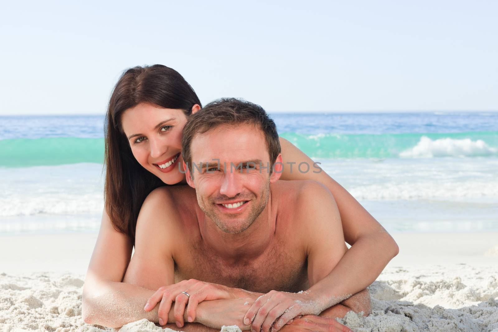 Couple lying down on the beach by Wavebreakmedia