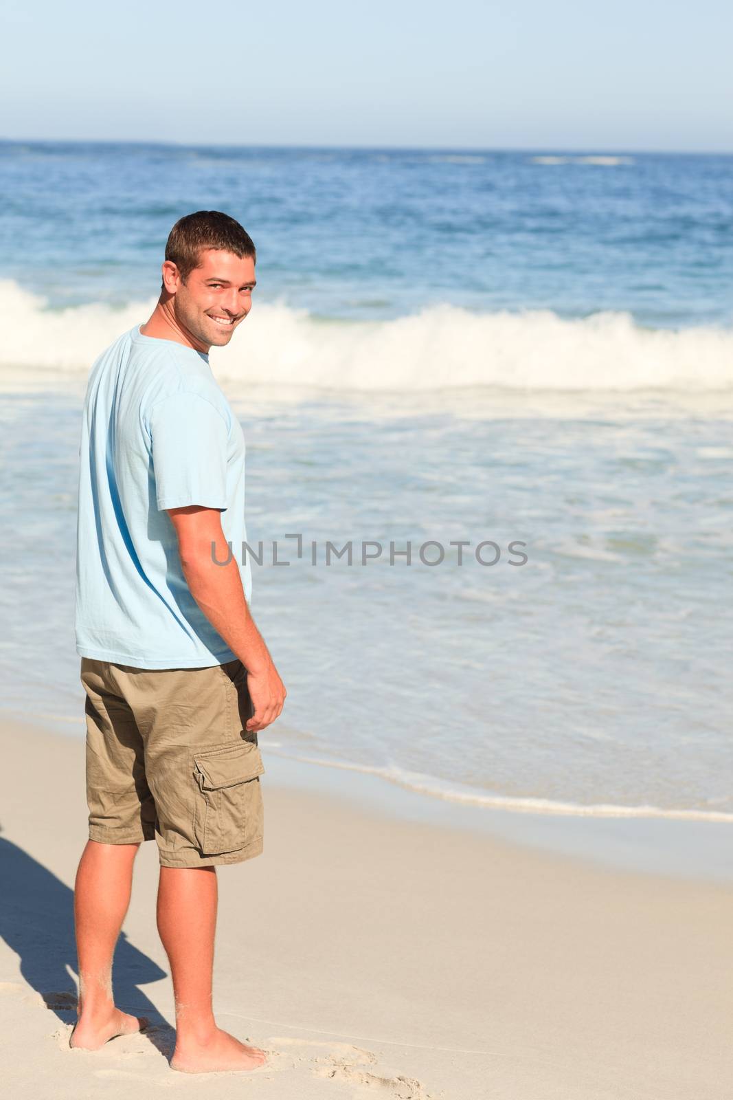 Handsome man walking on the beach by Wavebreakmedia