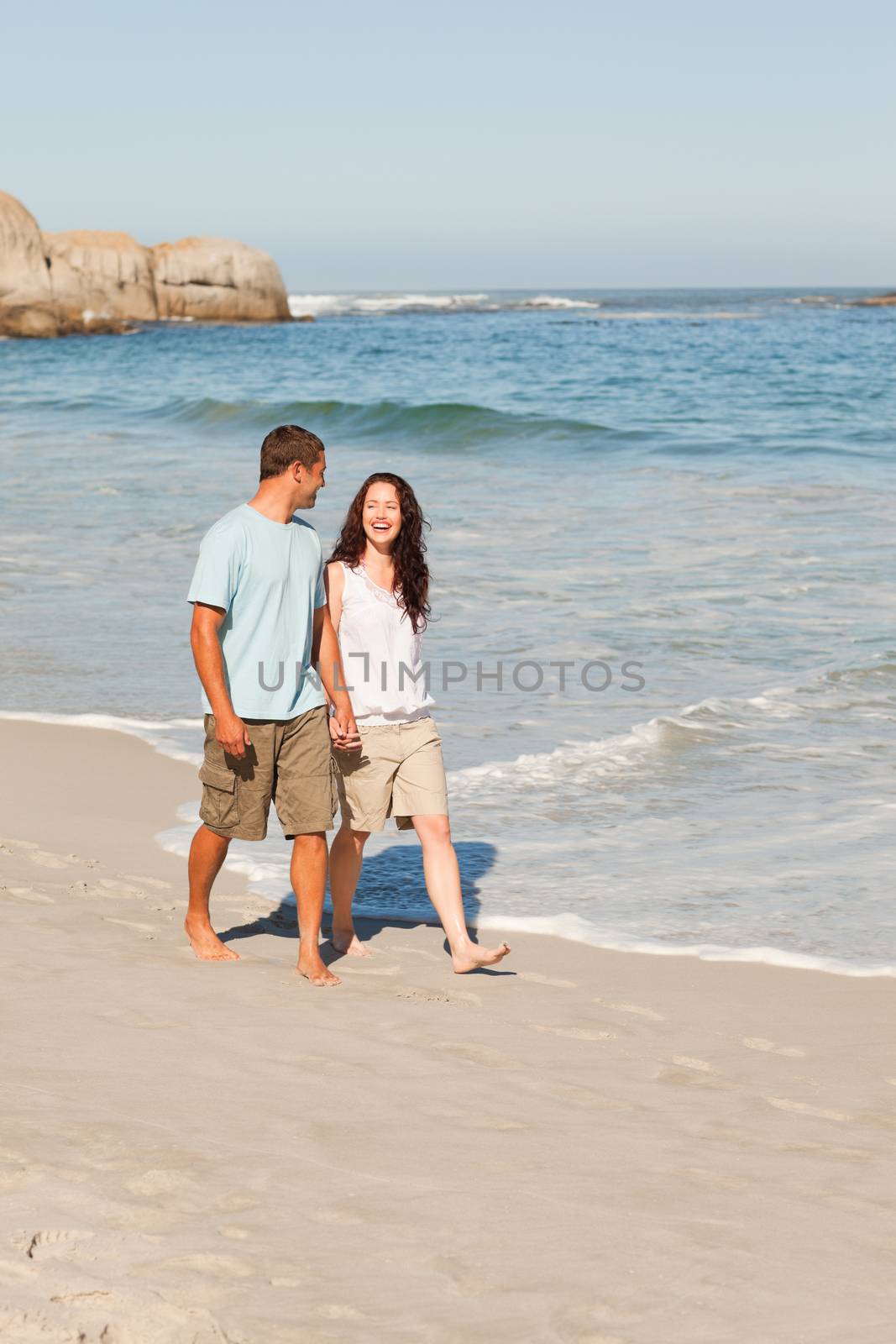 Couple walking on the beach by Wavebreakmedia