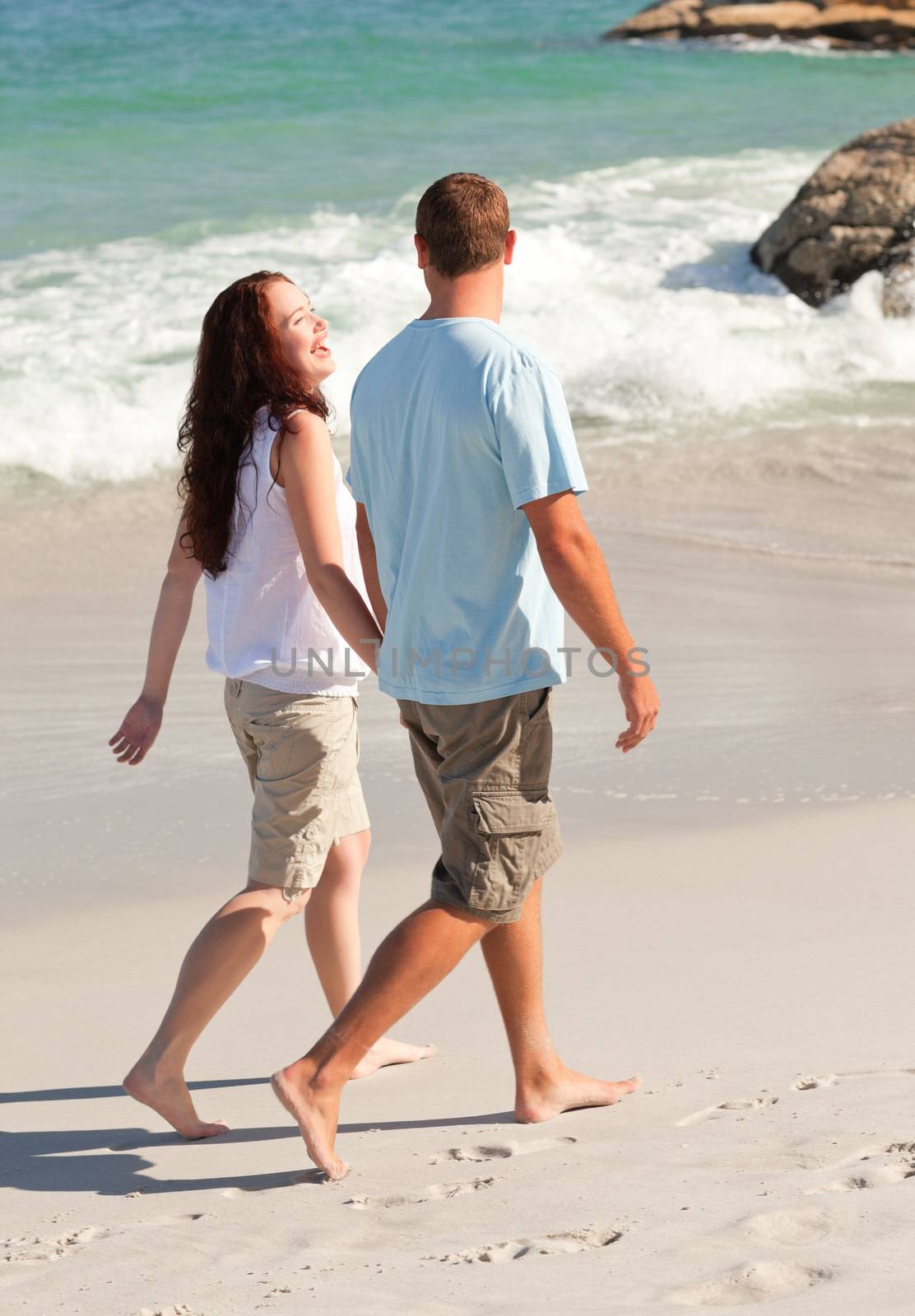 Lovers walking on the beach by Wavebreakmedia