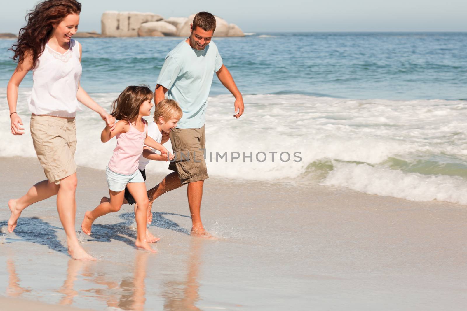Family running on the beach by Wavebreakmedia