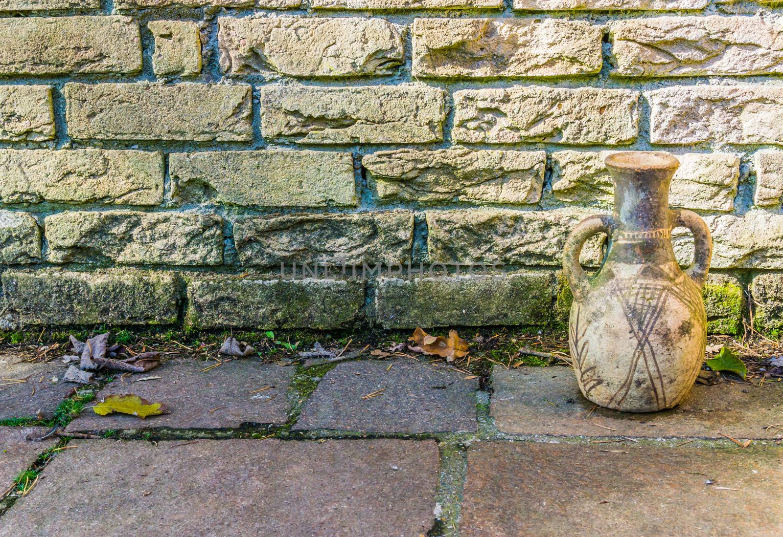 Dirty yellow brick wall with a old historical looking urn and stone pavements background texture by charlottebleijenberg