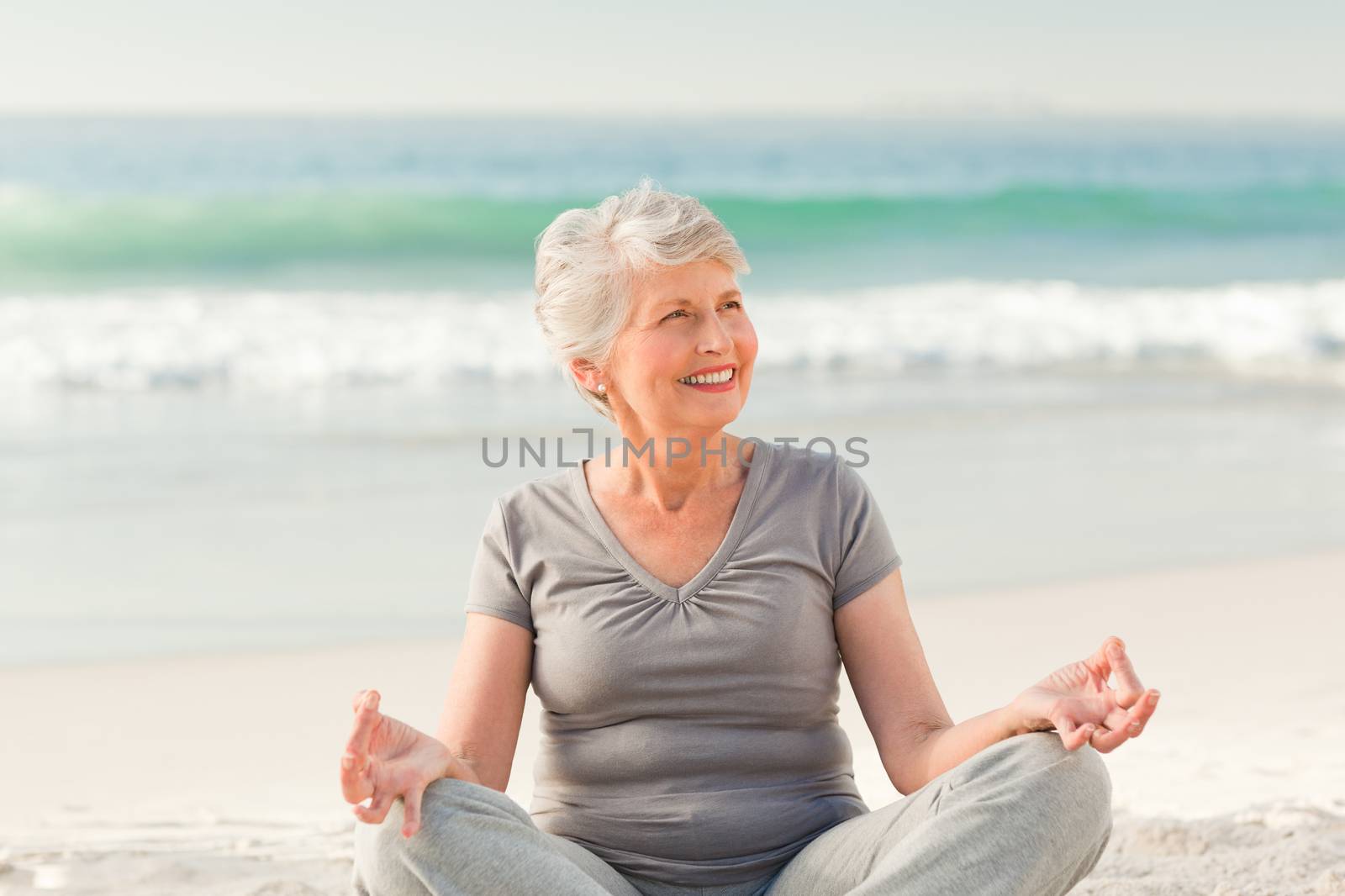 Senior woman practicing yoga on the beach by Wavebreakmedia