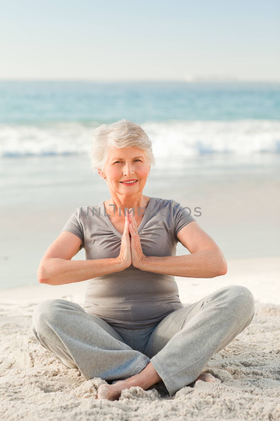 Senior woman practicing yoga on the beach