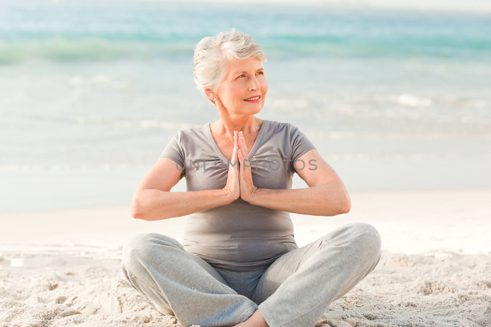 Senior woman practicing yoga on the beach by Wavebreakmedia