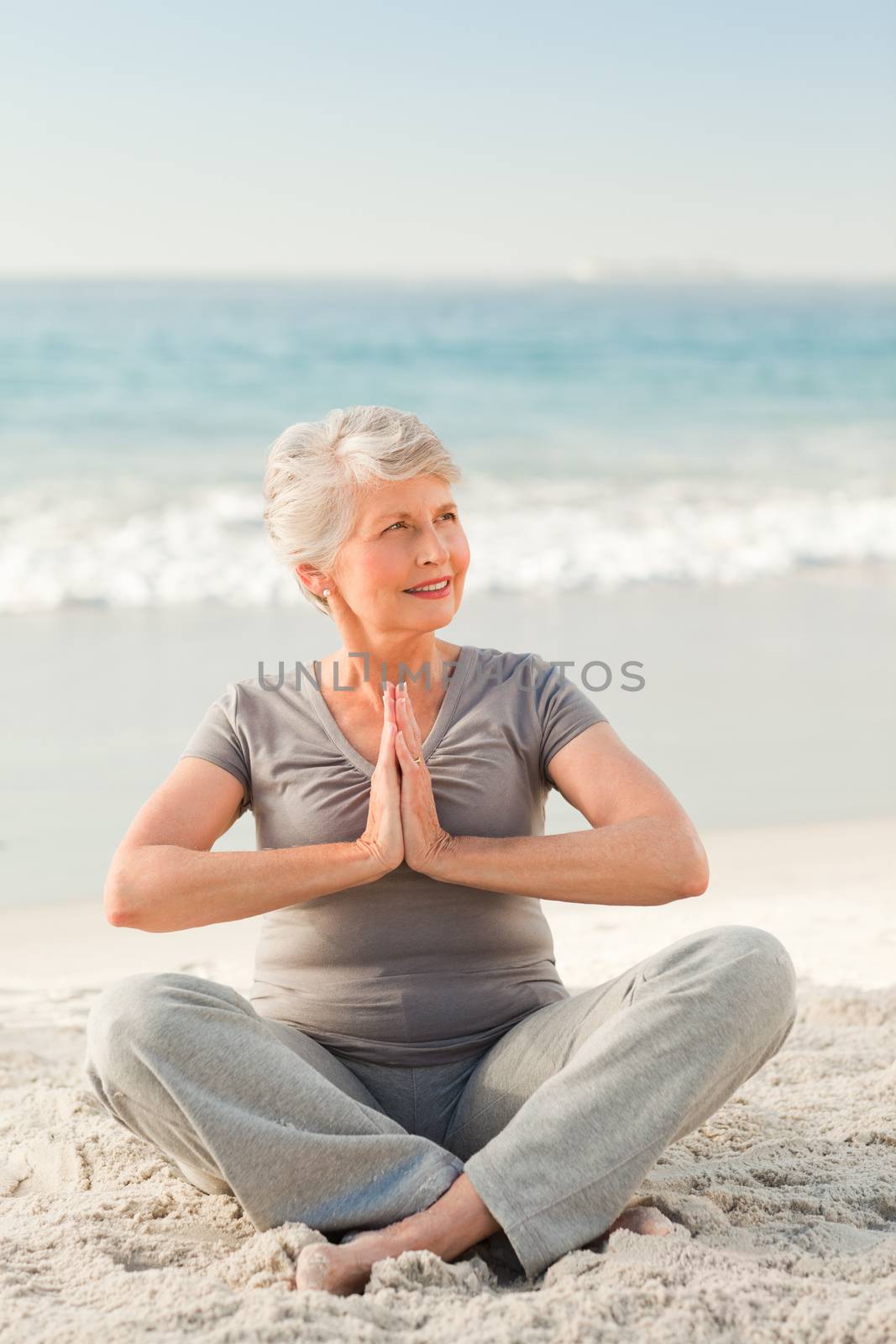 Senior woman practicing yoga on the beach by Wavebreakmedia