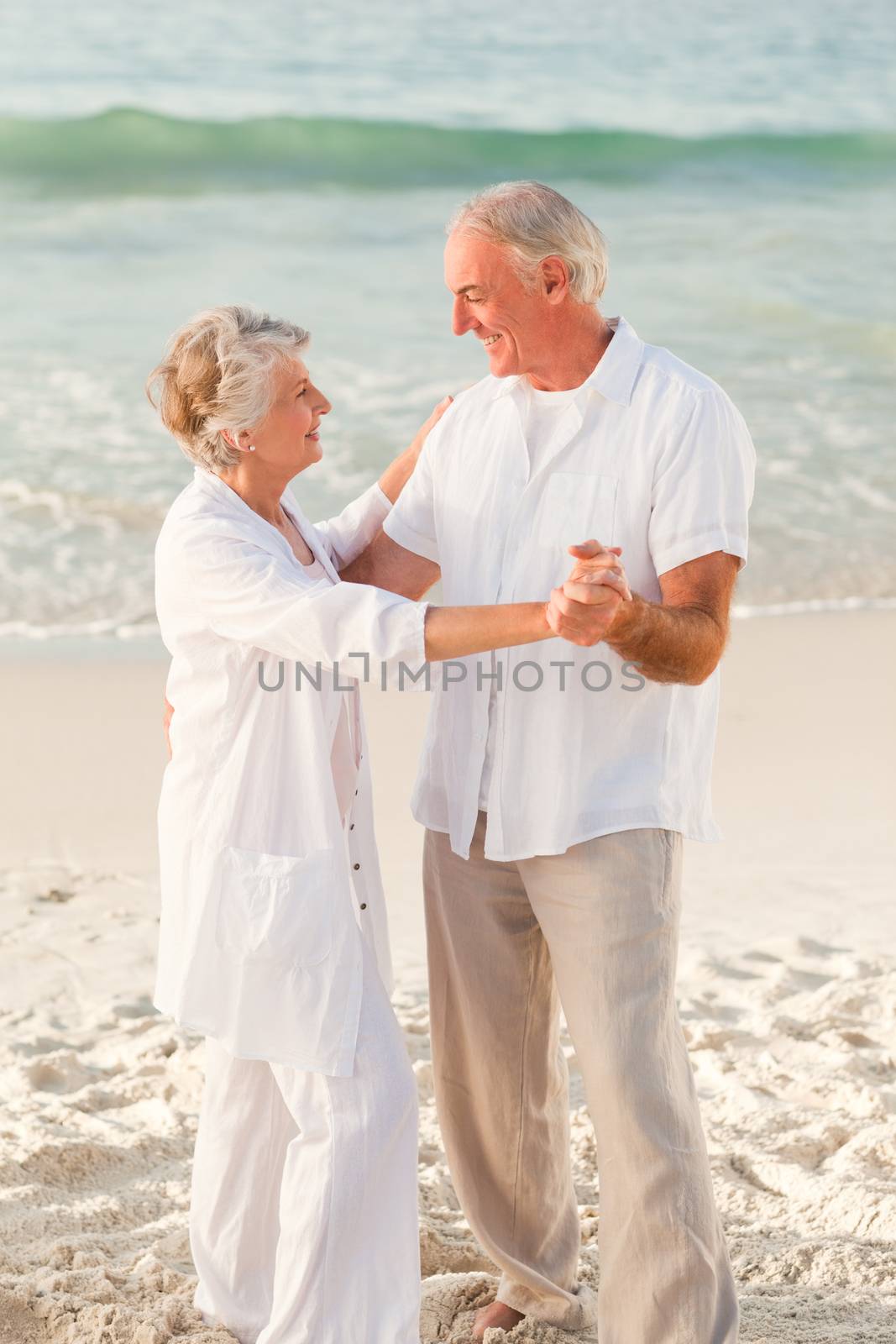 Elderly couple dancing on the beach by Wavebreakmedia
