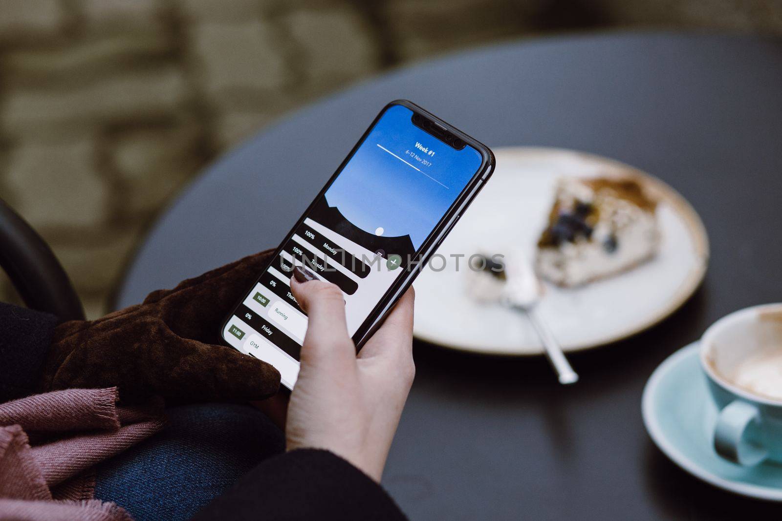 A image of woman's hands holding mobile phone with while having lunch in modern loft cafe at New Delhi. This image was taken on June 2019.