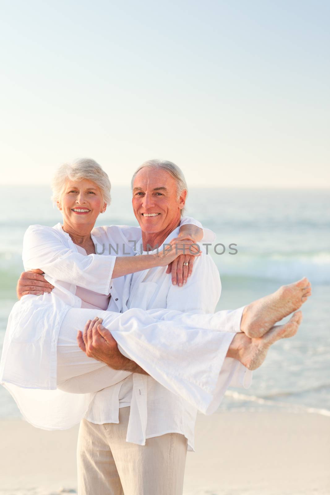Man carrying his wife on the beach by Wavebreakmedia
