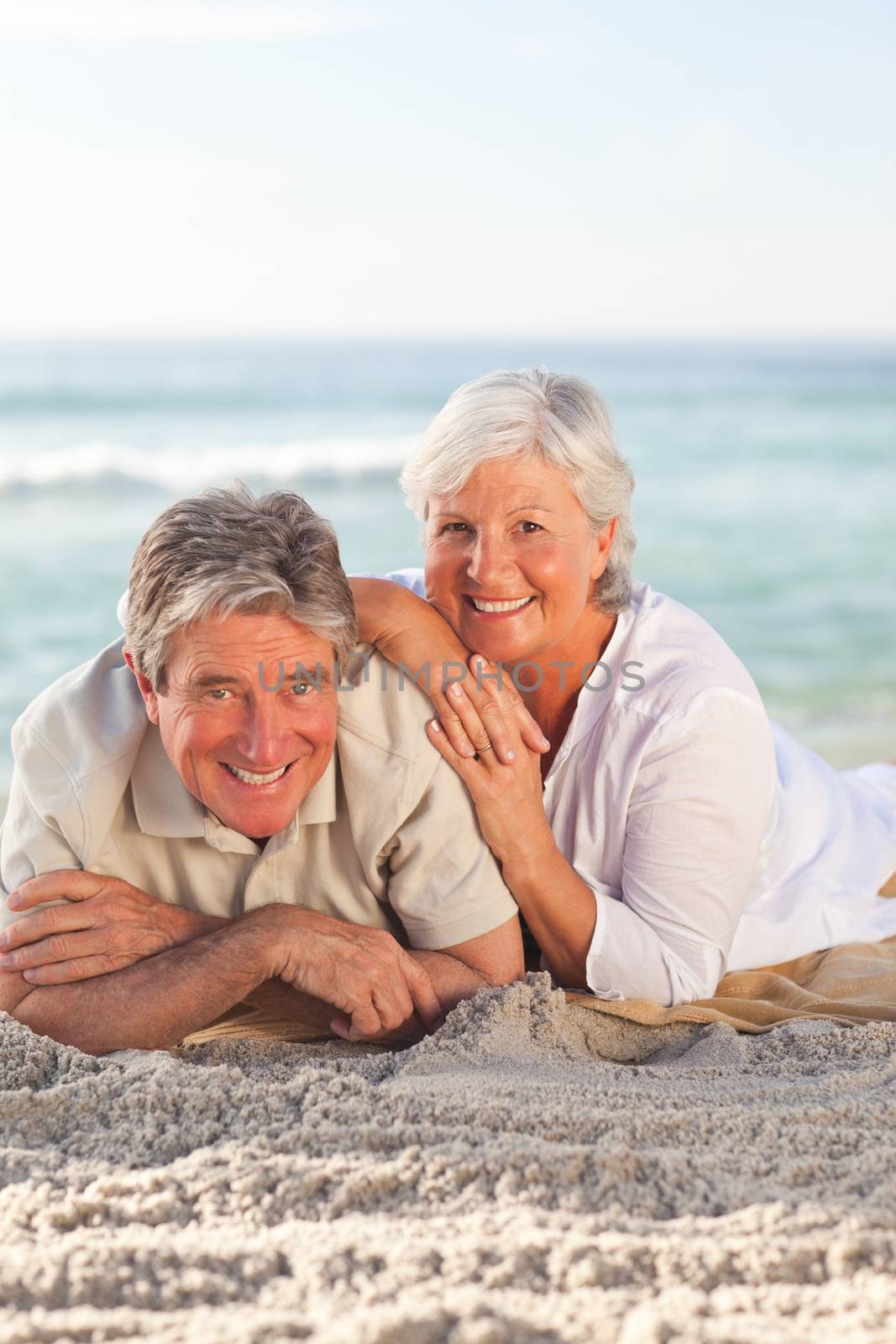 Elderly couple lying down on the beach by Wavebreakmedia