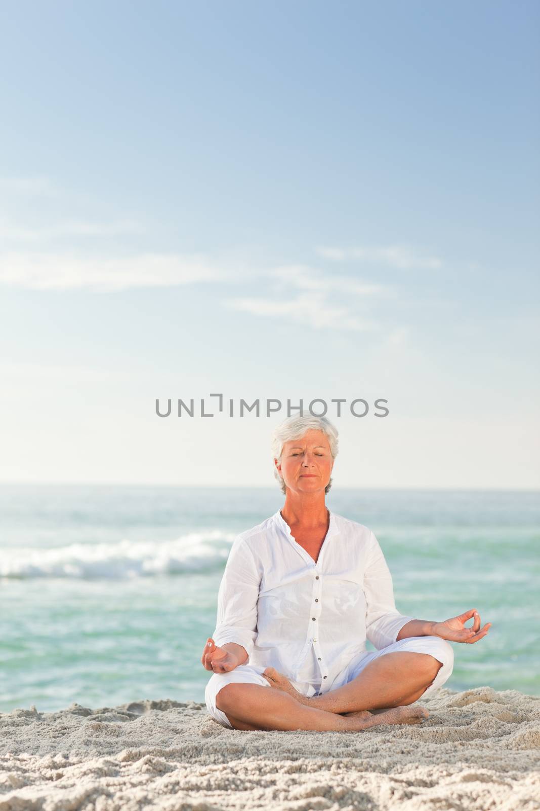 Mature woman practicing yoga on the beach by Wavebreakmedia