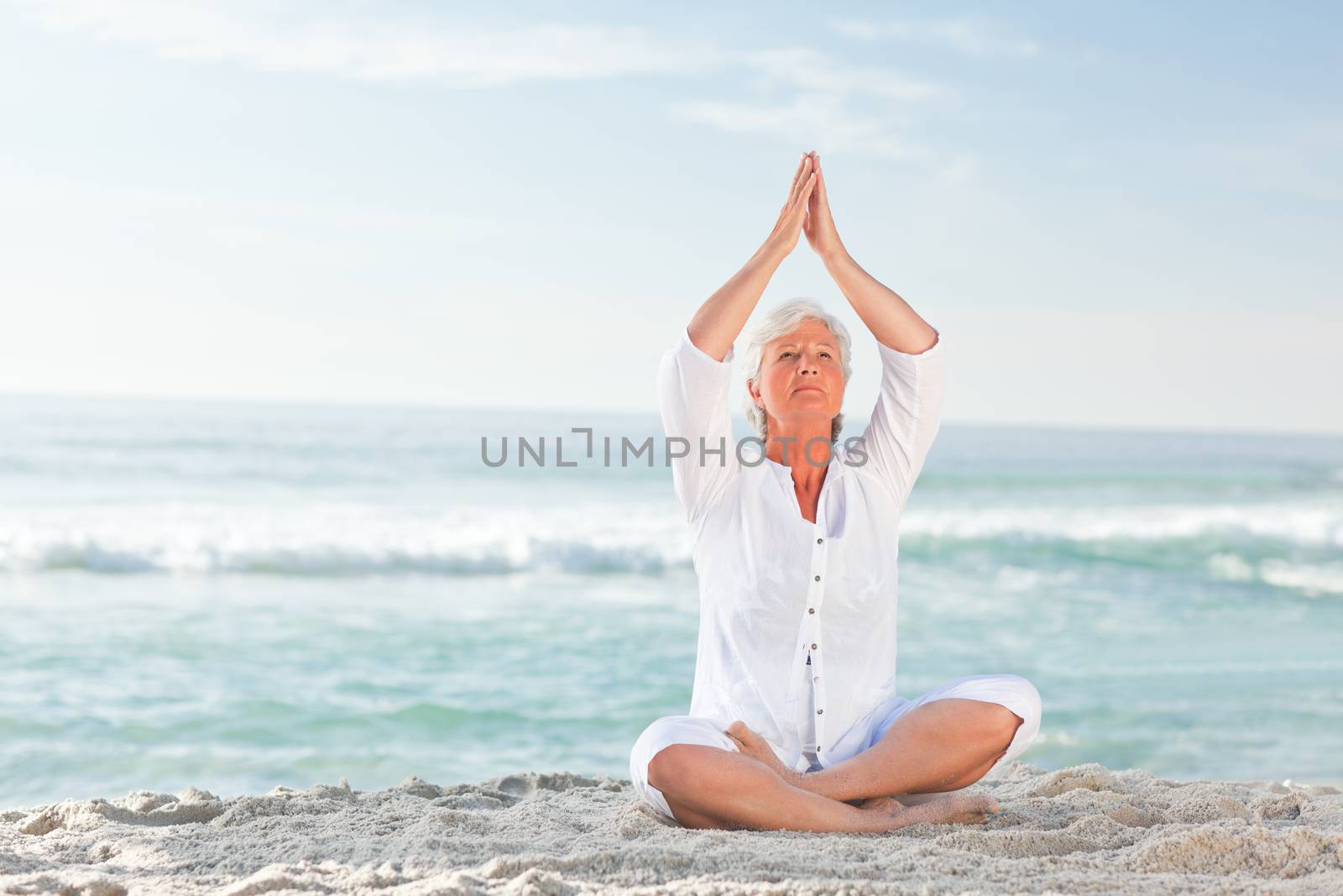 Mature woman practicing yoga on the beach by Wavebreakmedia