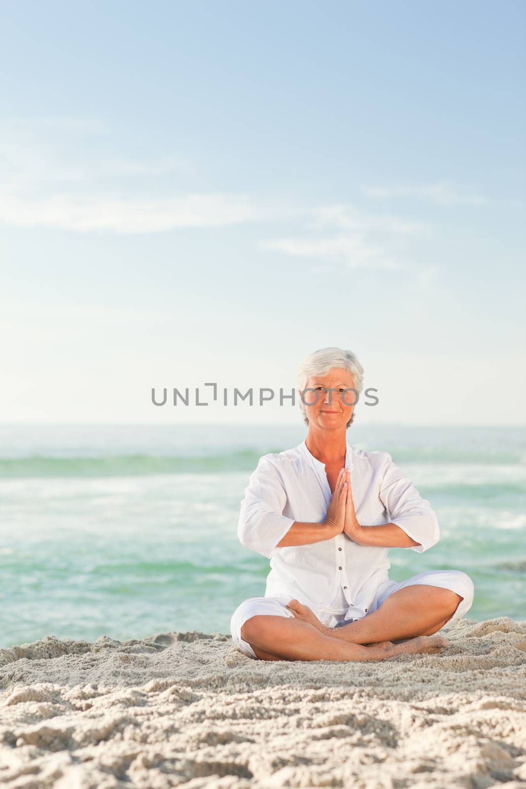 Mature woman practicing yoga on the beach