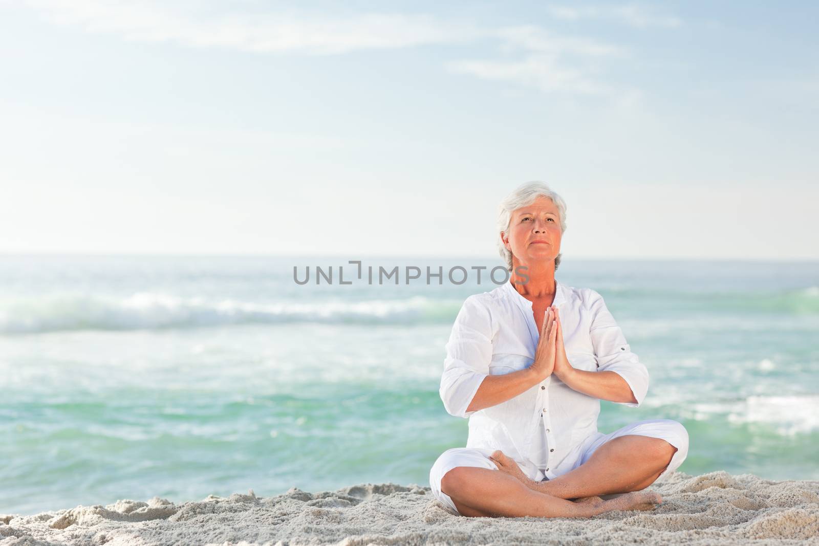 Mature woman practicing yoga on the beach by Wavebreakmedia