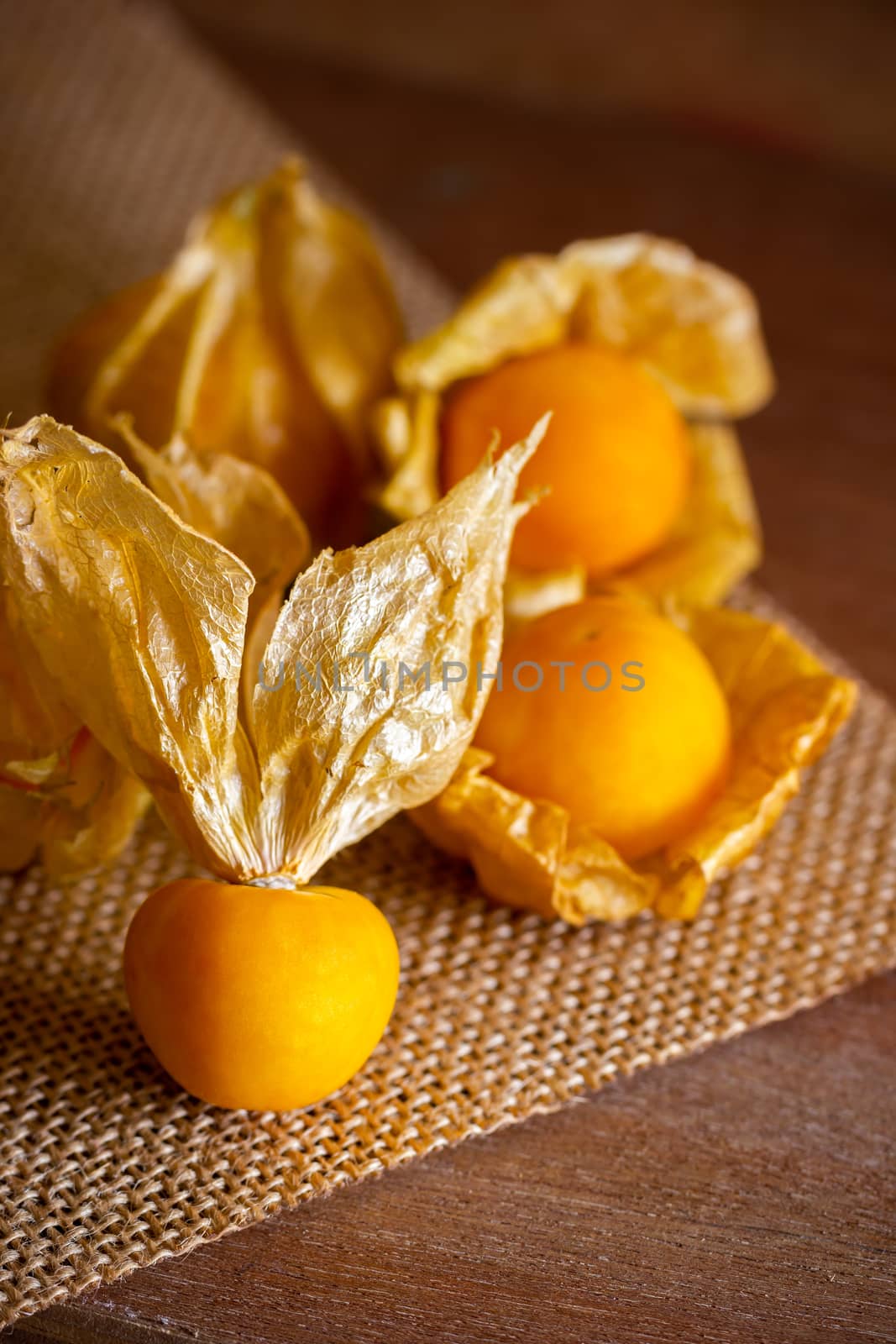 Closeup cape gooseberry on wooden table. Concept of health care. by SaitanSainam