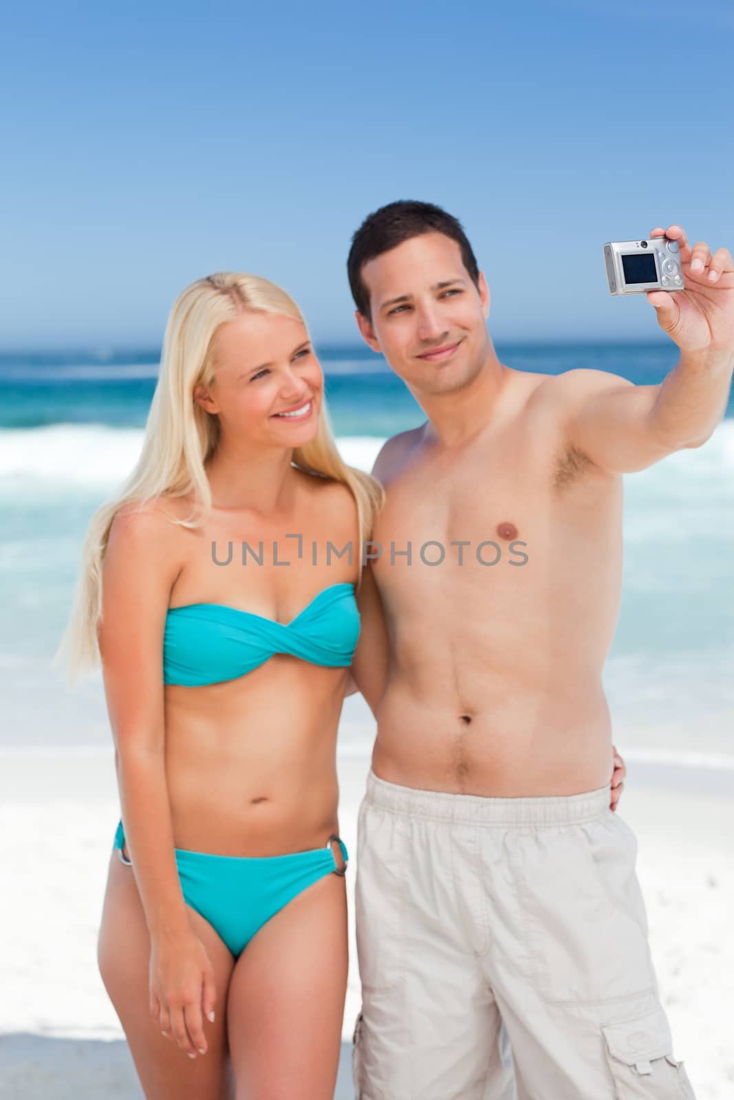 Couple taking a photo of themselves on the beach by Wavebreakmedia