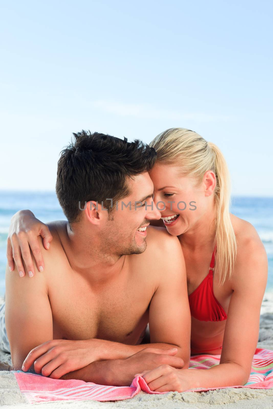 Lovers lying down on the beach by Wavebreakmedia