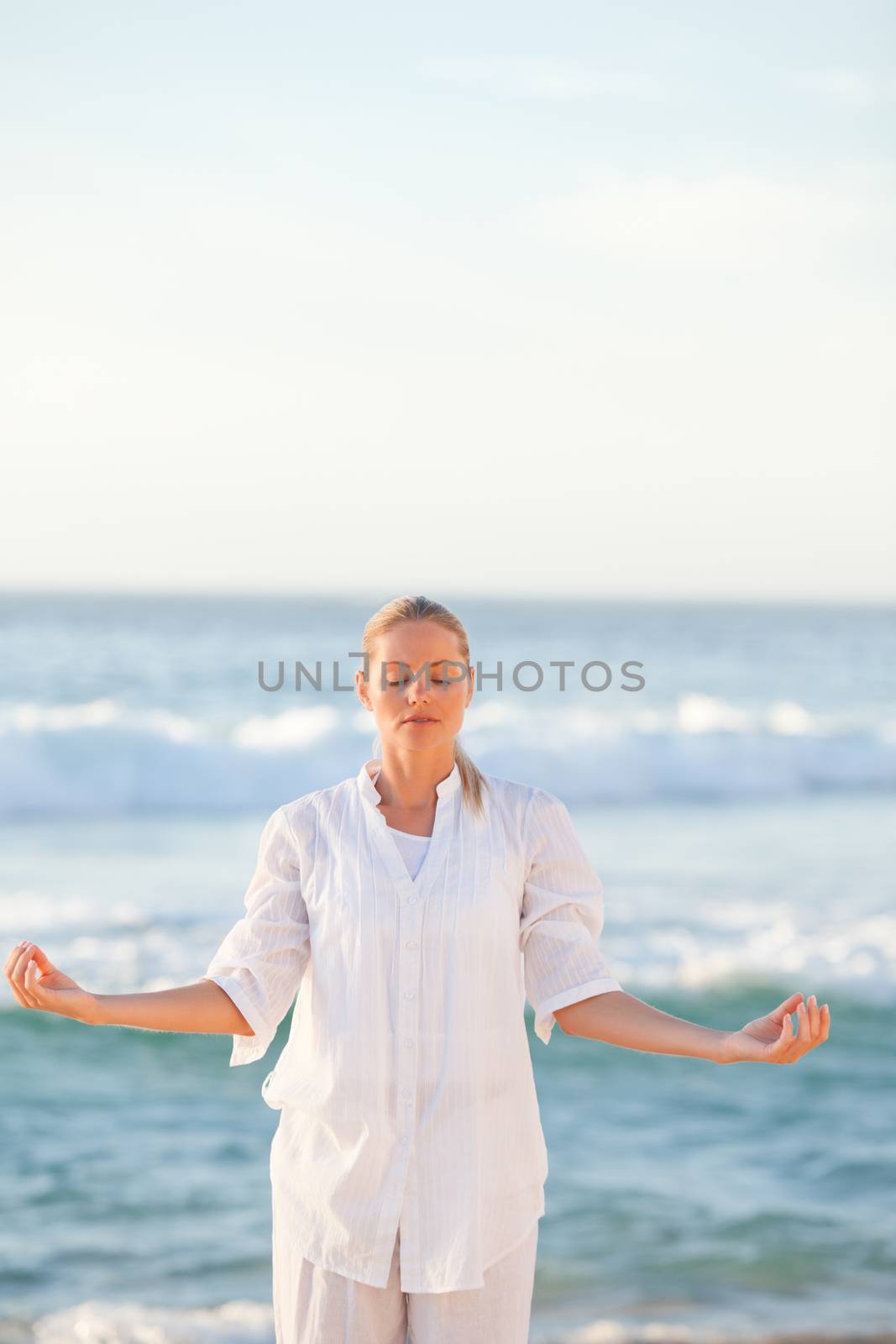 Woman practicing yoga at the beach by Wavebreakmedia
