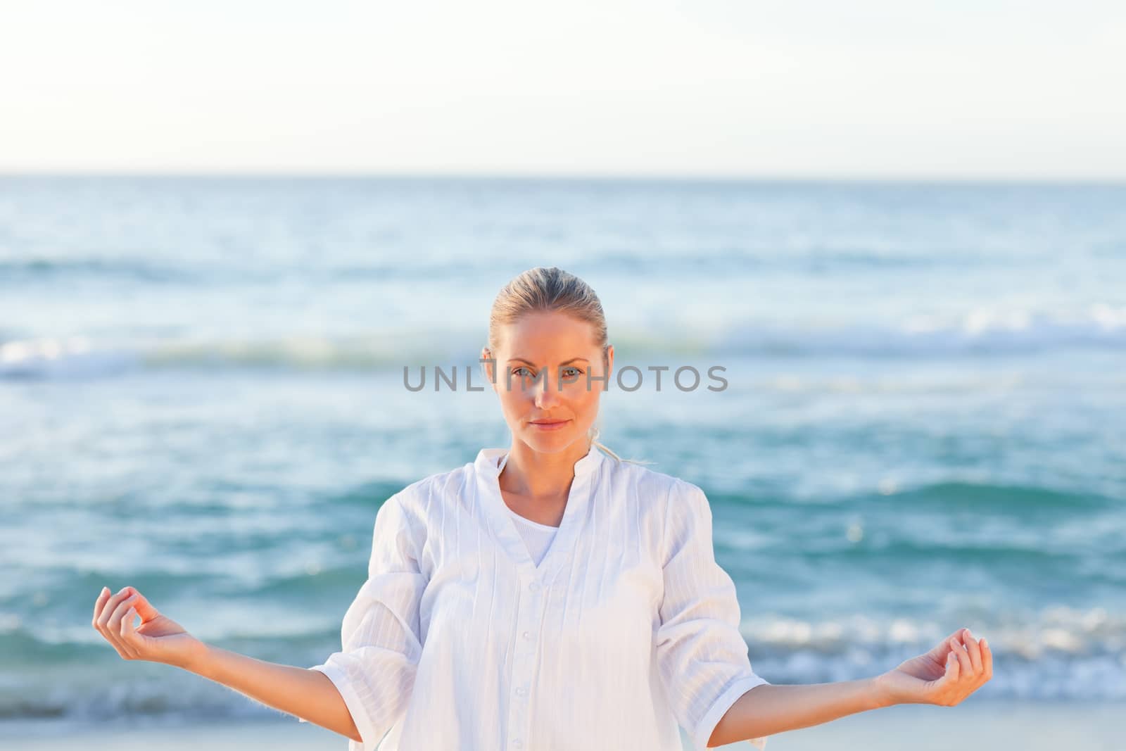 Active woman practicing yoga on the beach