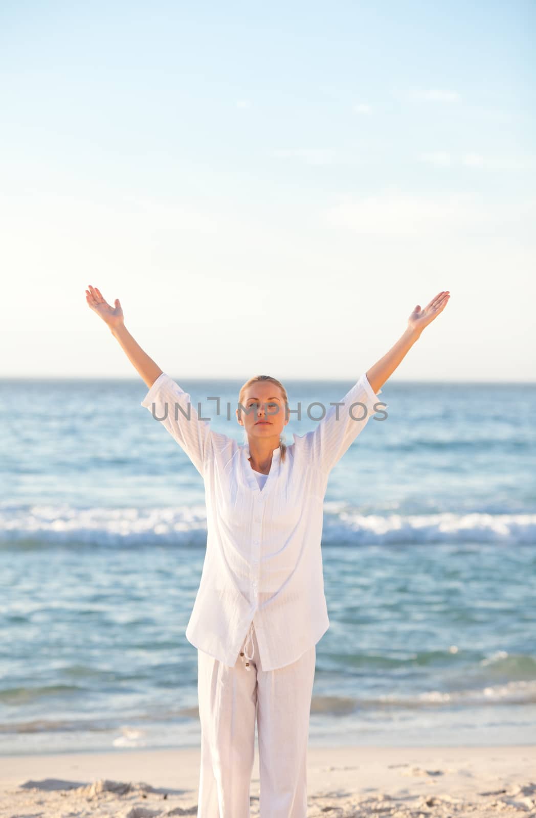 Woman practicing yoga at the beach against the sea