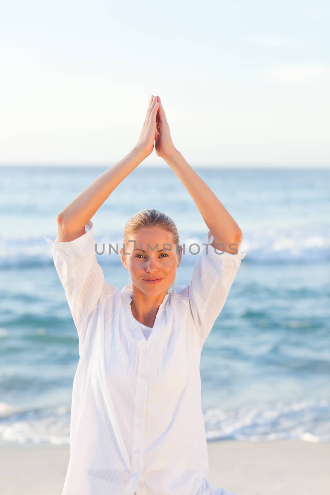 Active woman practicing yoga on the beach