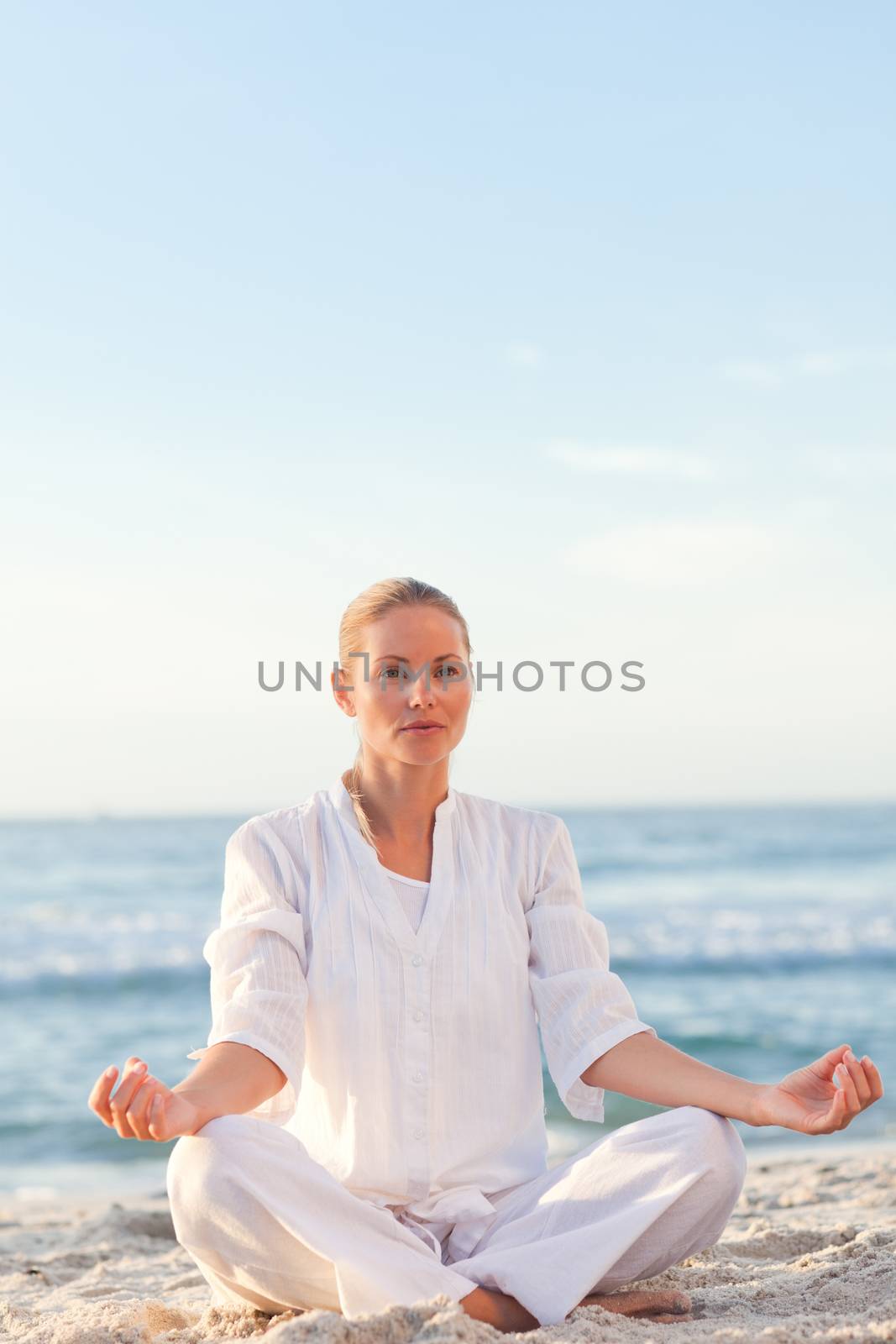 Peaceful woman practicing yoga against the sea by Wavebreakmedia