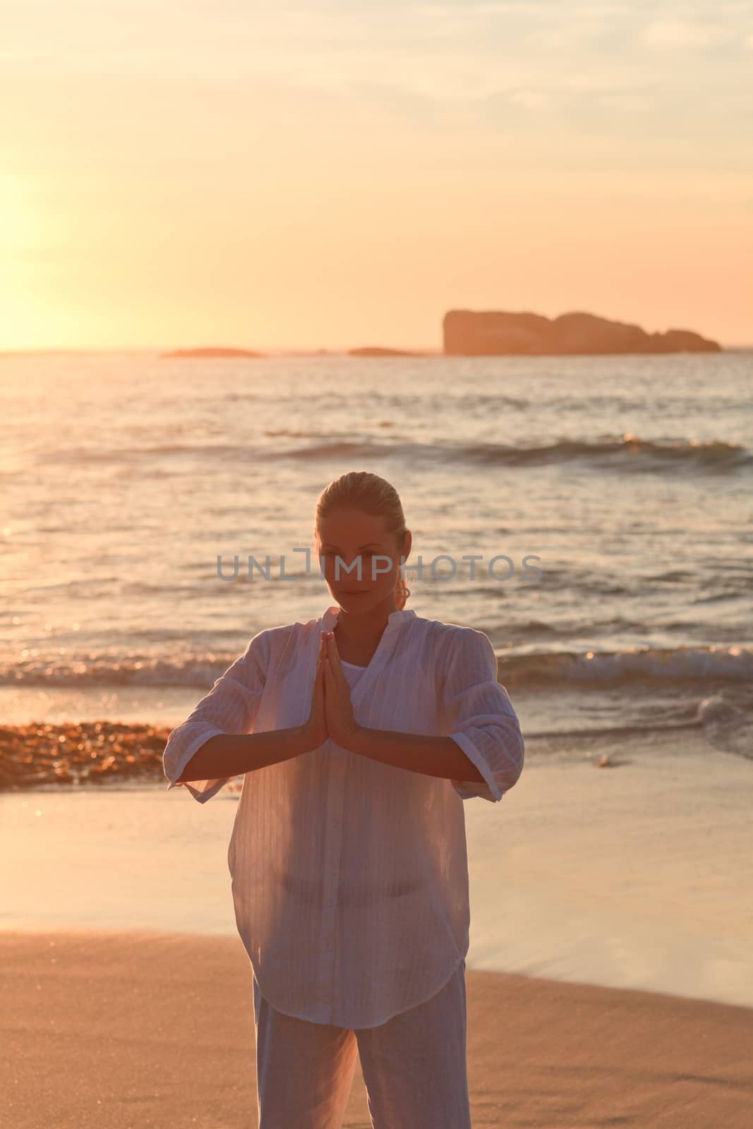 Woman practicing yoga during the sunset by Wavebreakmedia