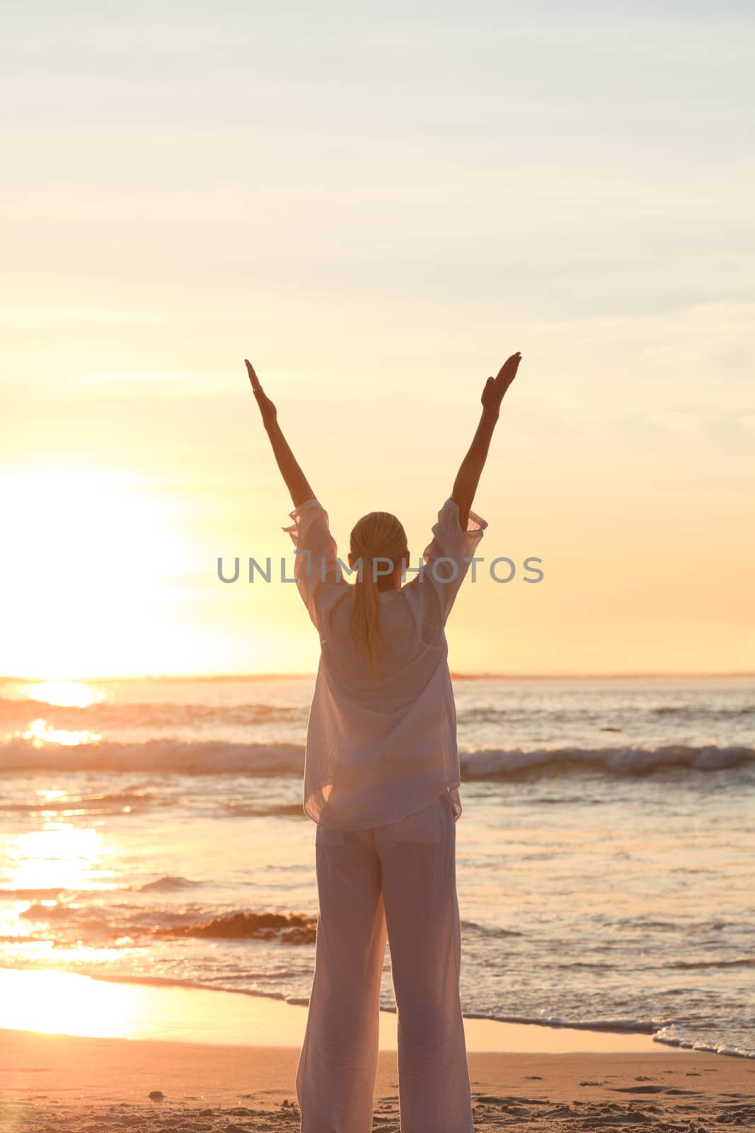 Woman practicing yoga during the sunset against the sea