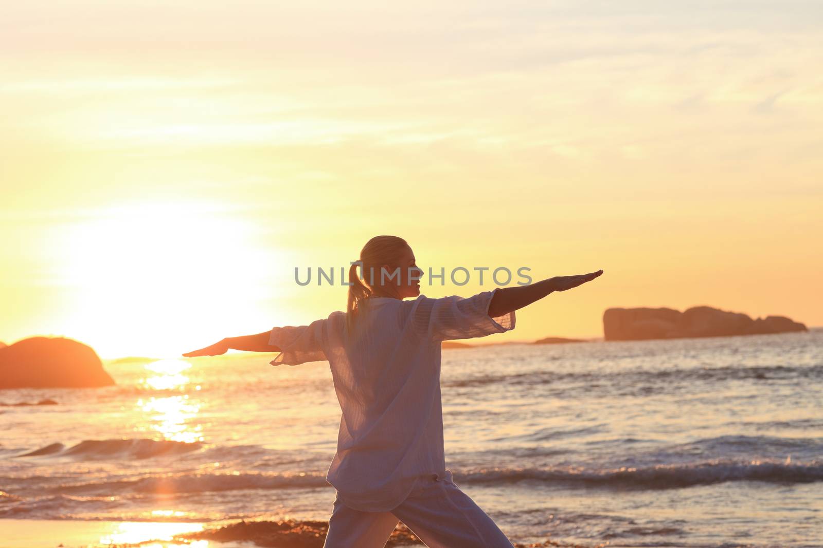 Woman practicing yoga during the sunset at the beach by Wavebreakmedia