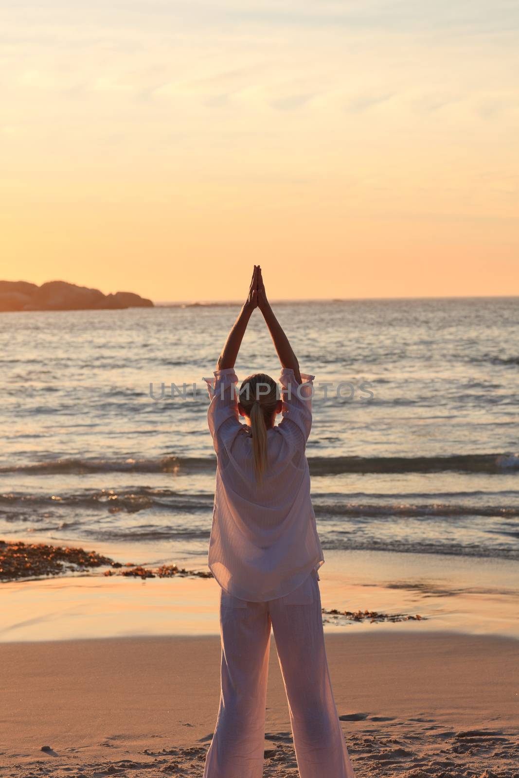 Woman practicing yoga during the sunset at the beach by Wavebreakmedia