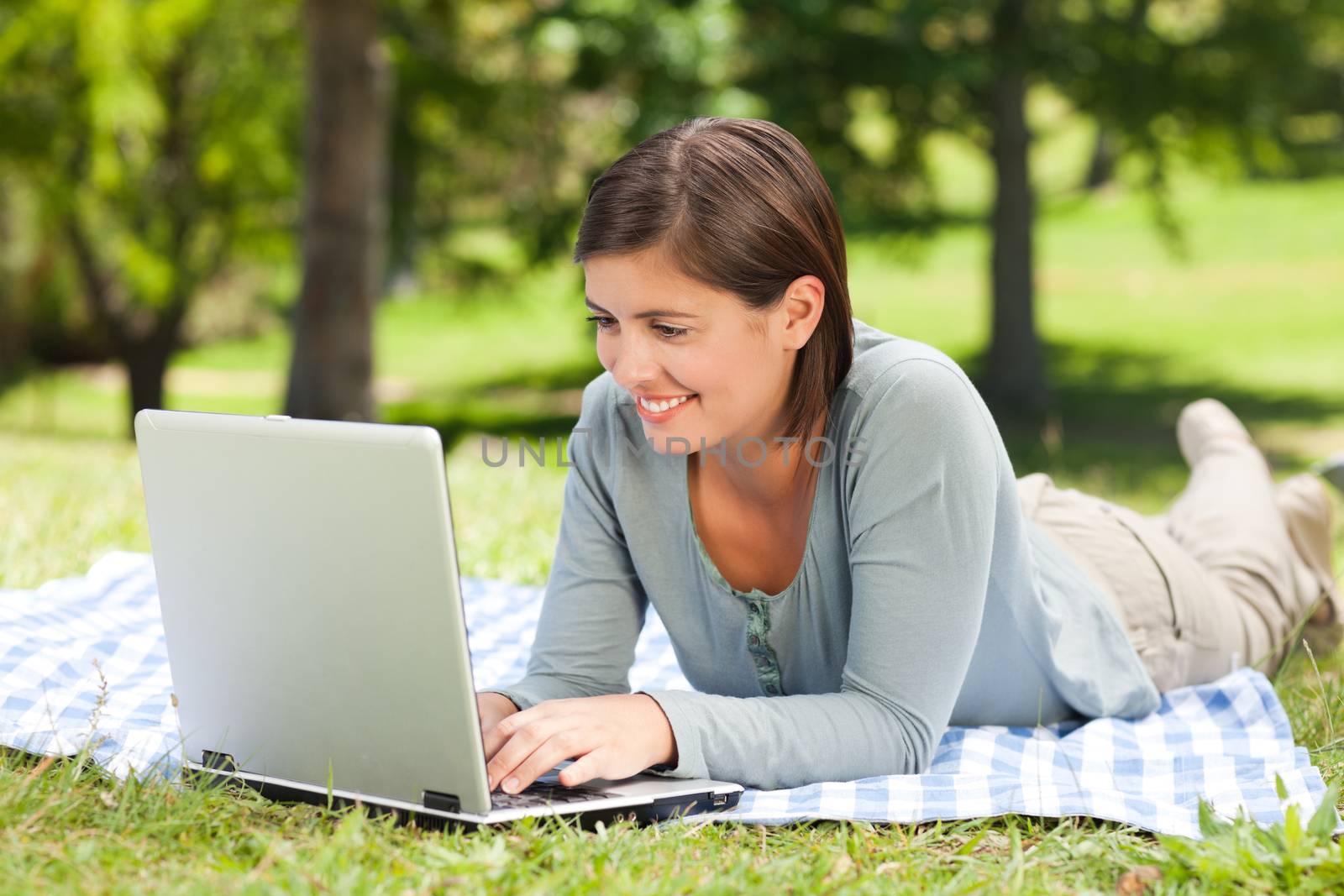 Woman working on her laptop in the park by Wavebreakmedia