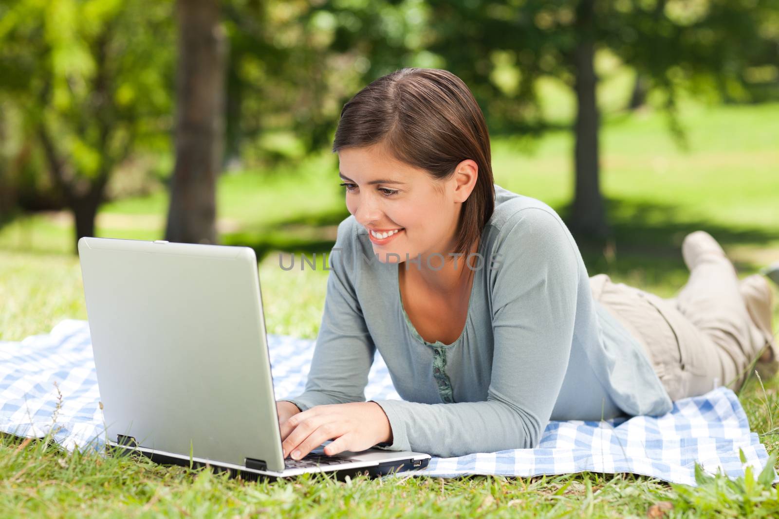 Woman working on her laptop in the park during the summer