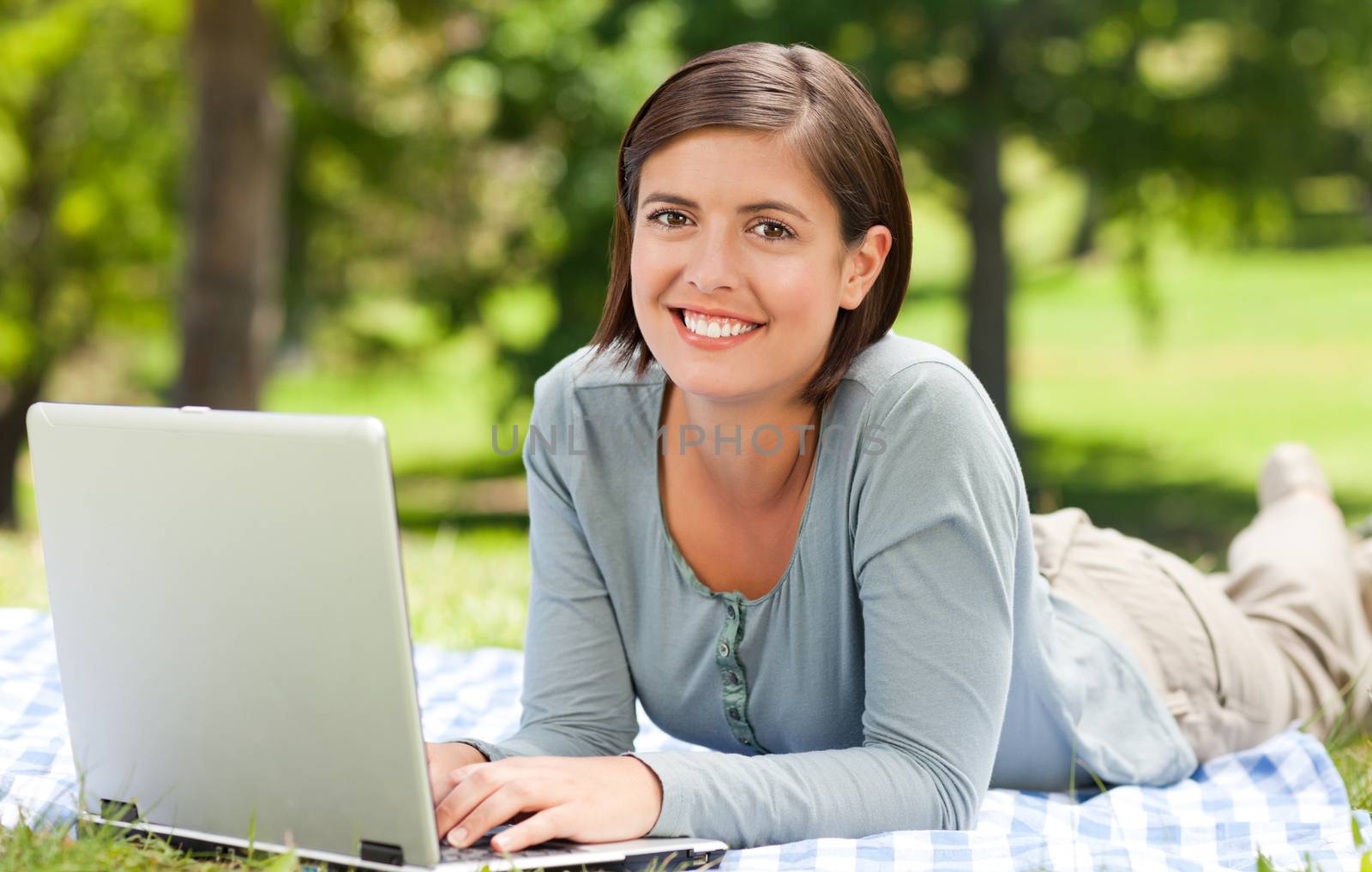 Woman working on her laptop in the park by Wavebreakmedia