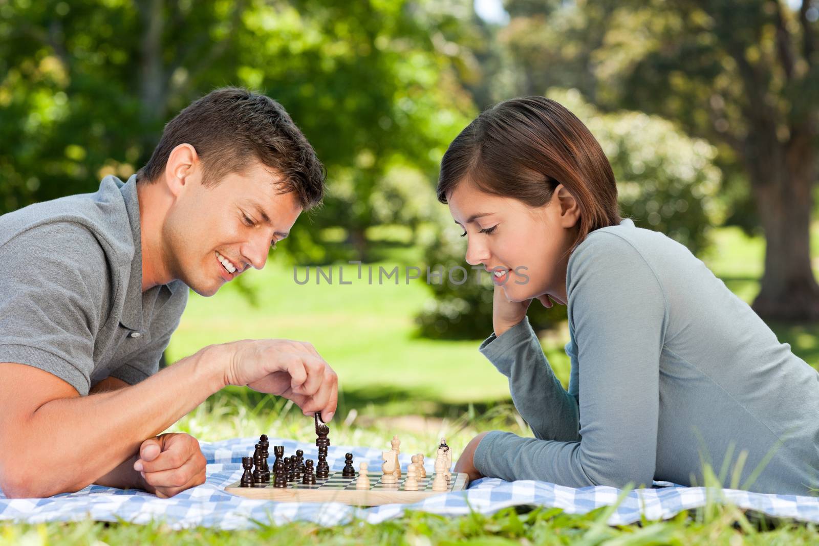 Couple playing chess in the park during the summer