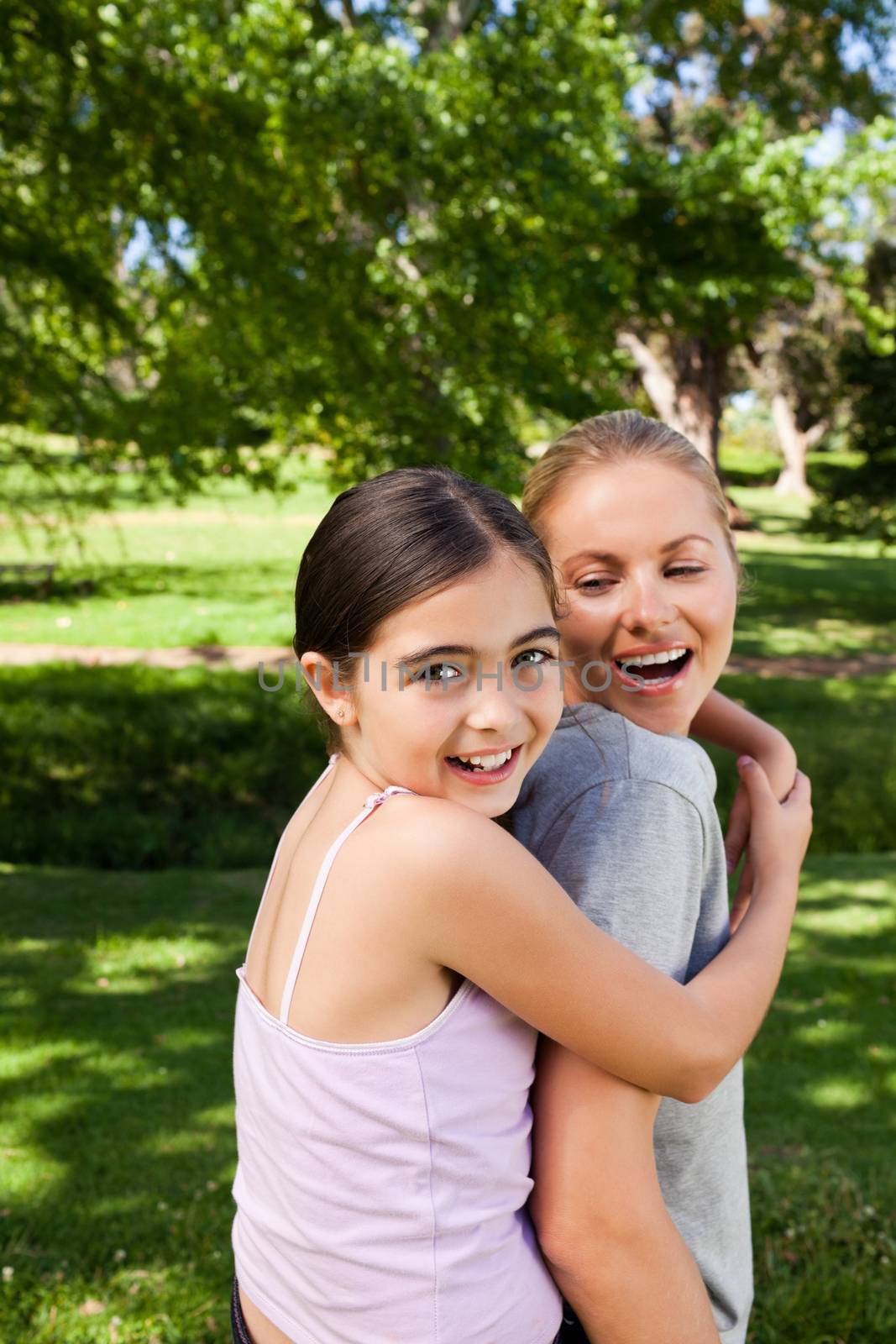 Mother and her daughter laughting in the park during the summer