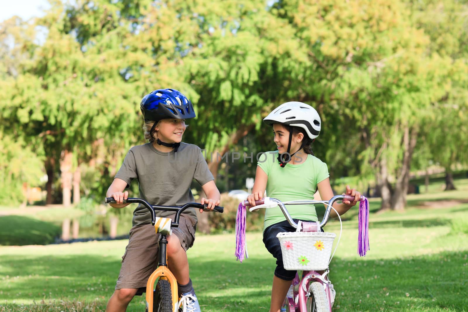 Brother and sister with their bikes in a park during the summer