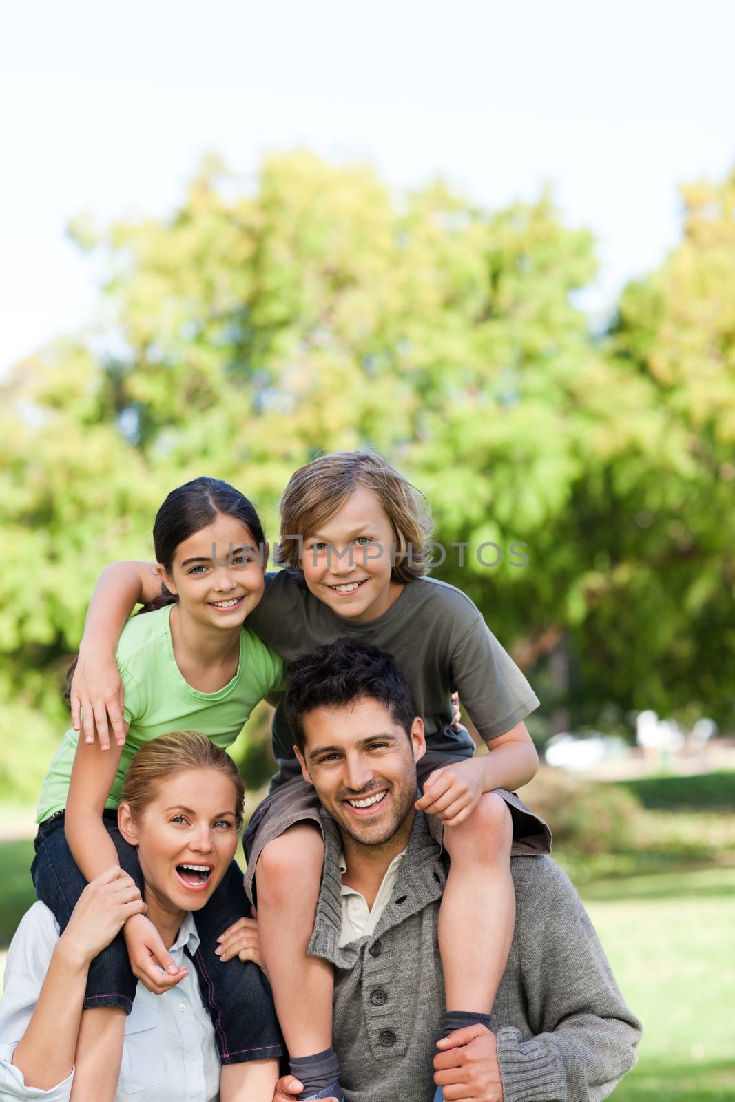 Parents giving children a piggyback during the summer by Wavebreakmedia