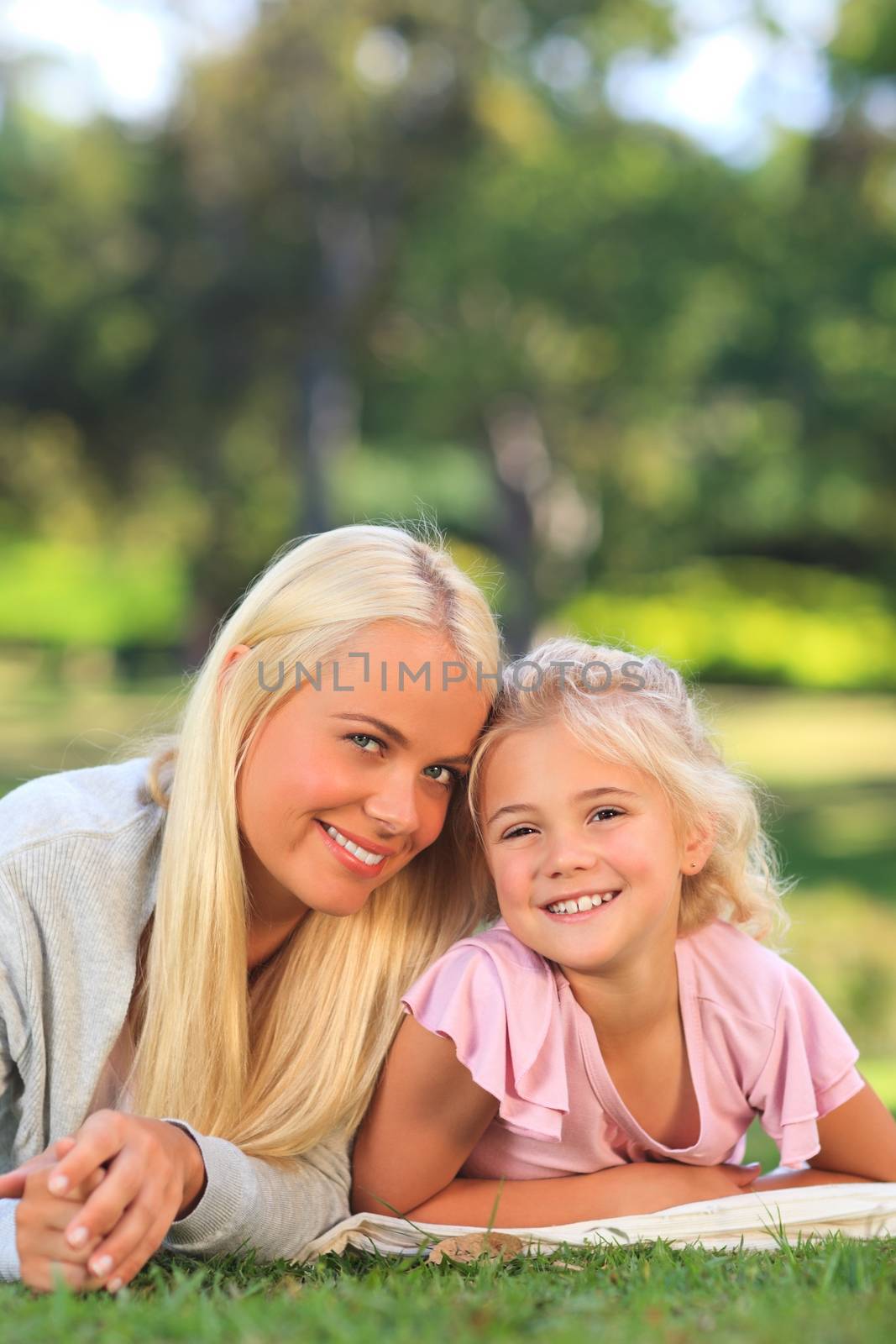 Mother with her daughter lying down in the park during the summer