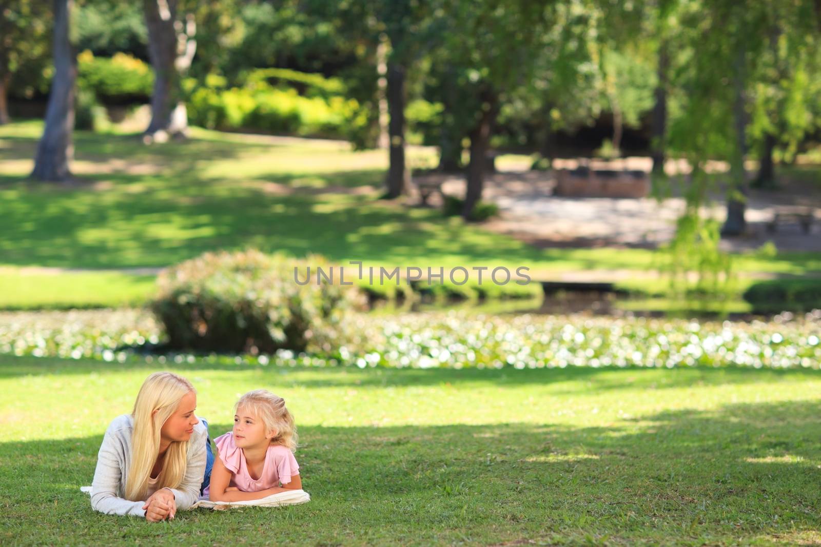 Mother with her daughter lying down during the summer in the park