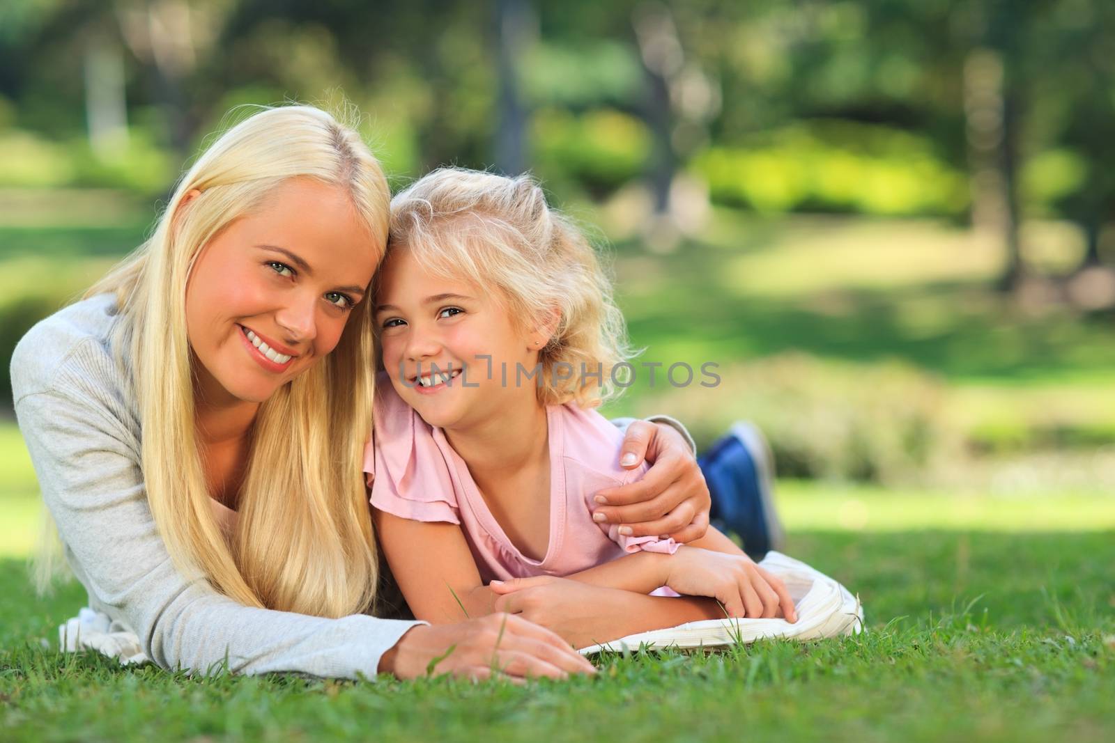 Mother with her daughter lying down in the park during the summer
