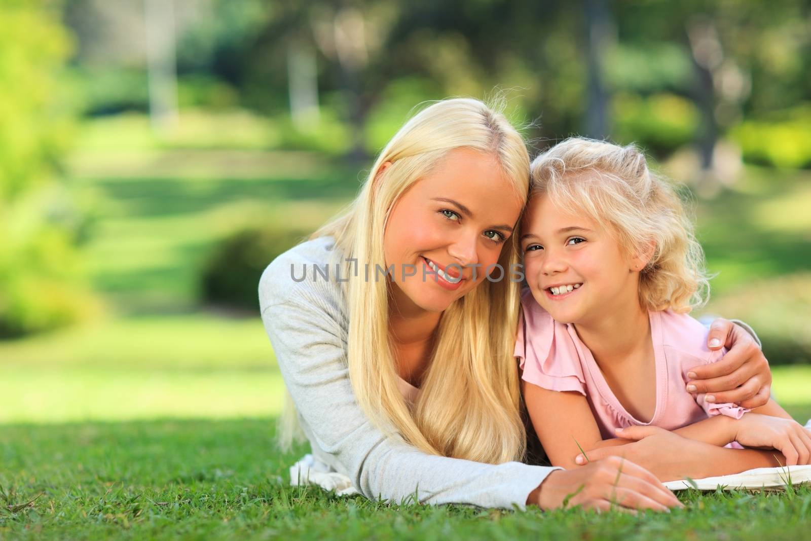 Mother with her daughter lying down in the park during the summer
