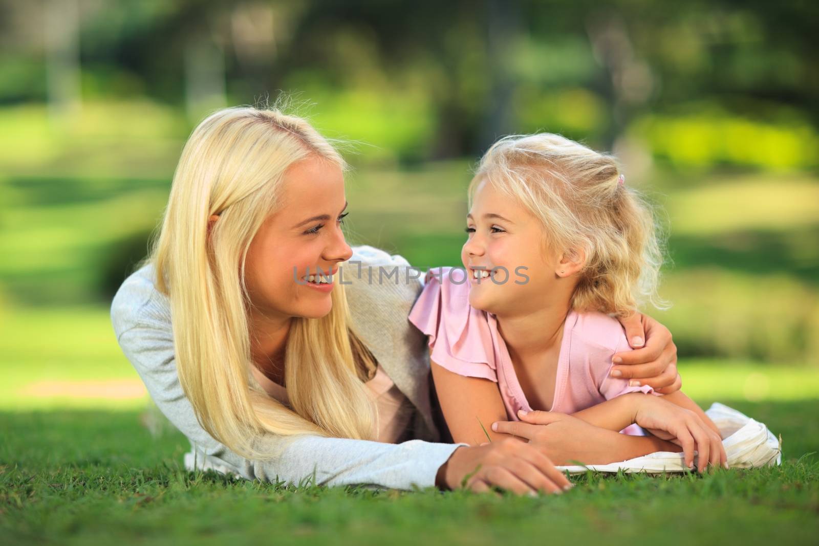 Mother with her daughter lying down in the park during the summer