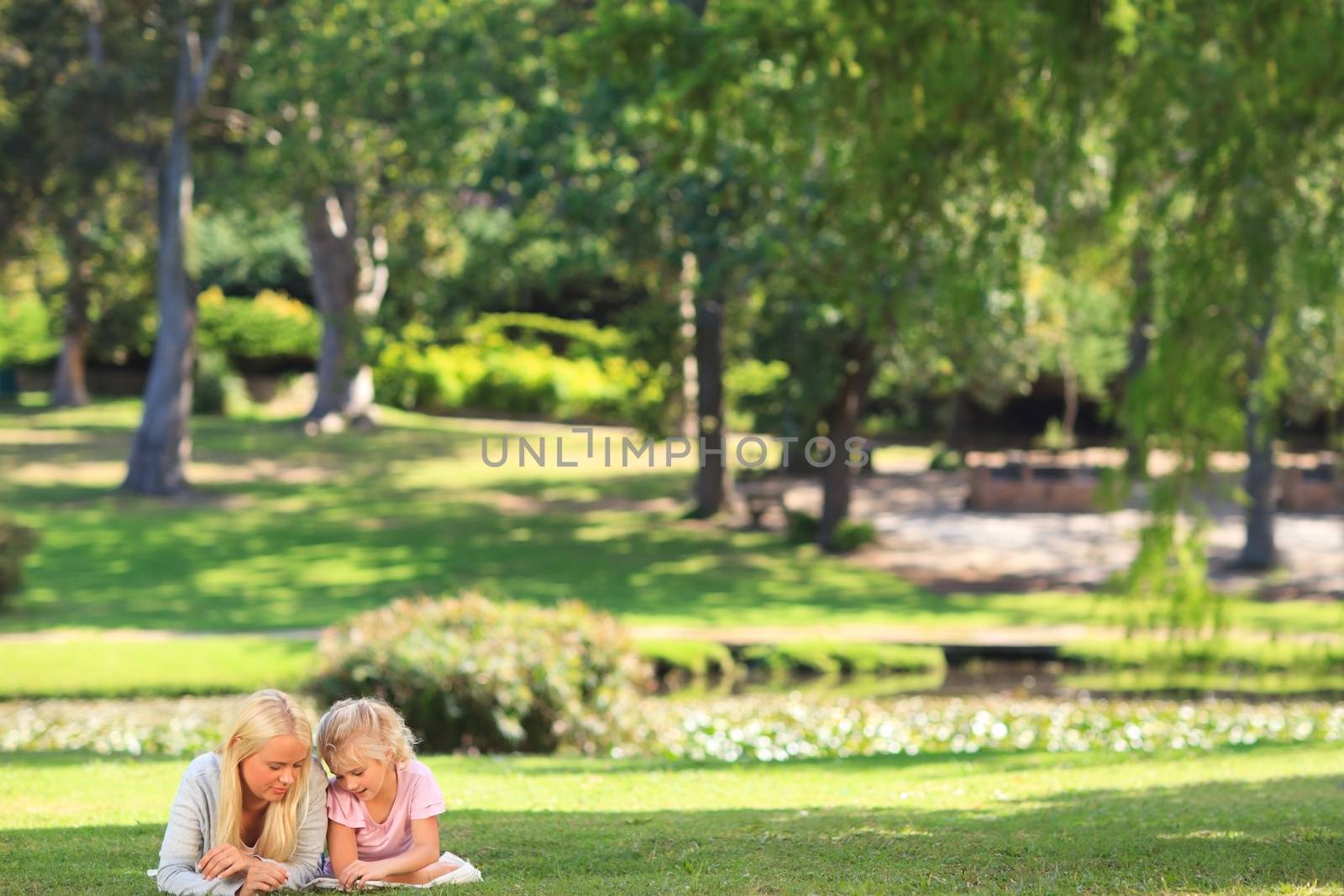 Mother with her daughter lying down in the park during the summer