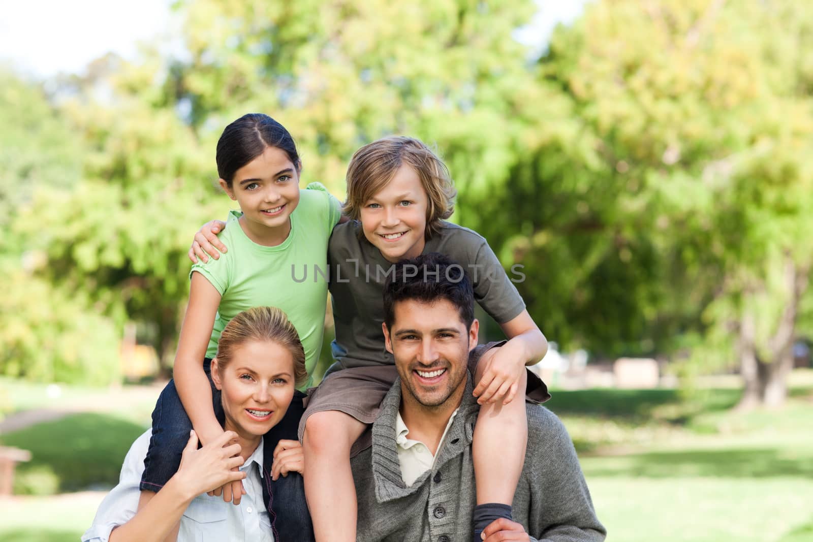 Parents giving children a piggyback in a park by Wavebreakmedia