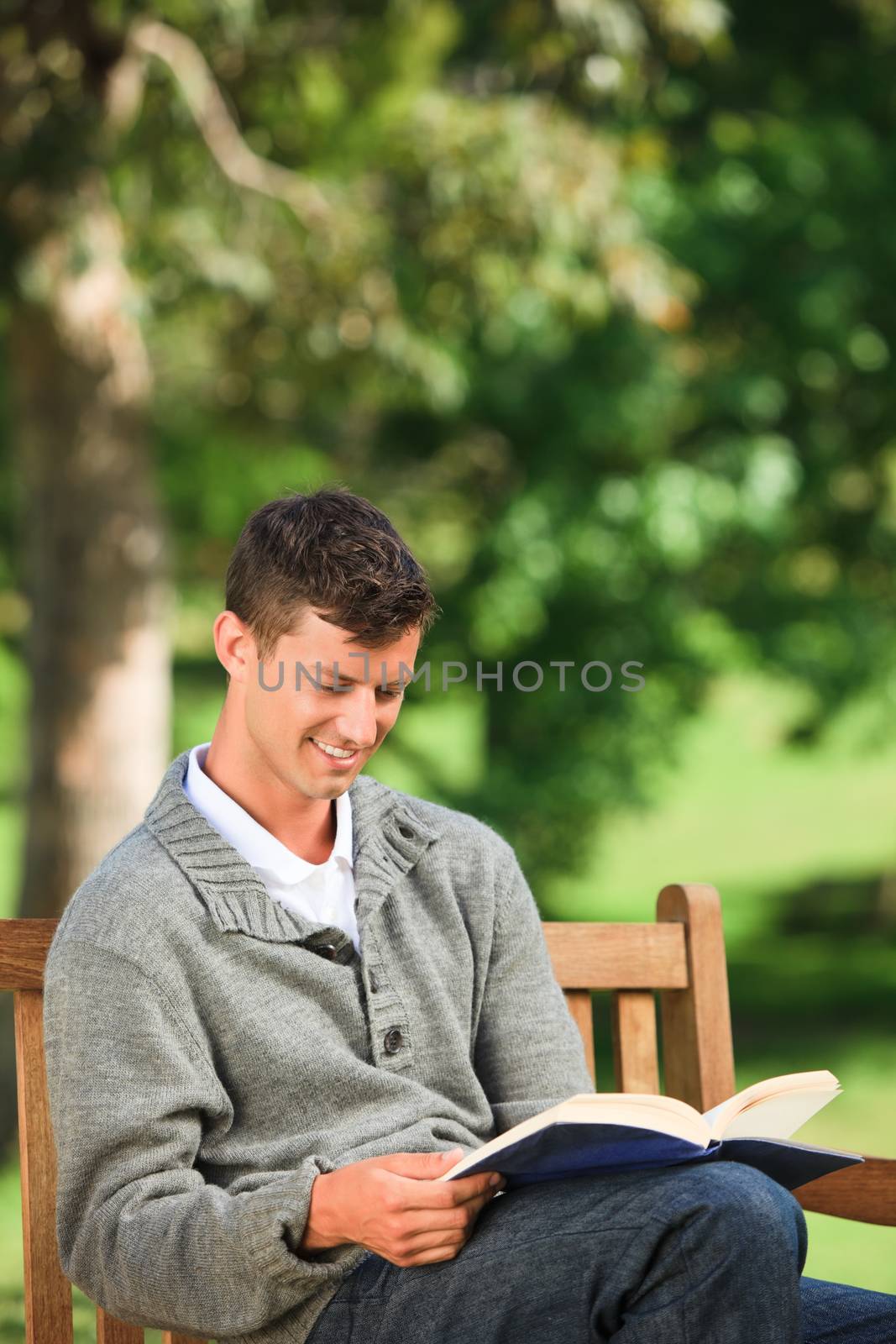 Young man reading his book on the bench by Wavebreakmedia