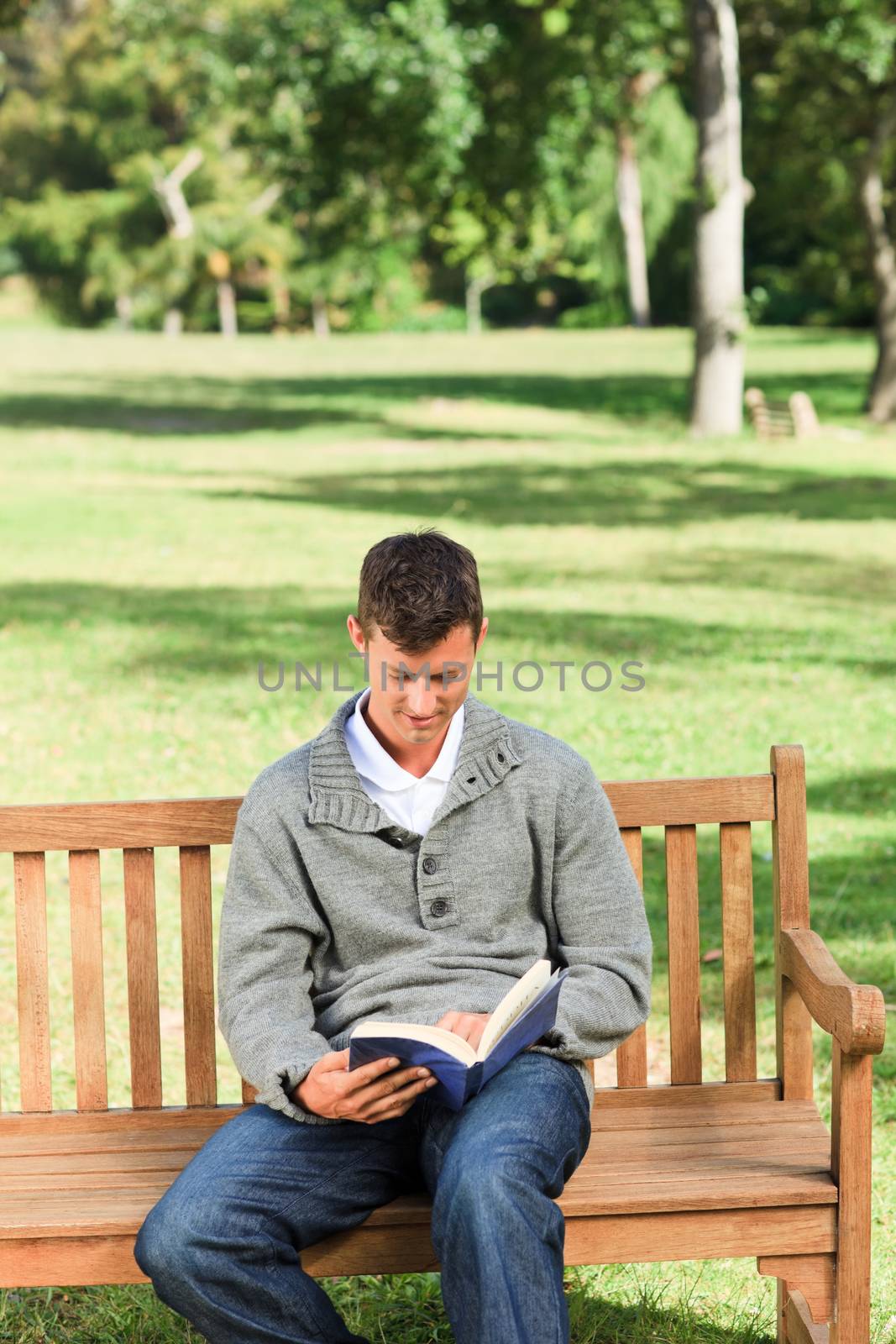 Young man reading his book on the bench during the summer 
